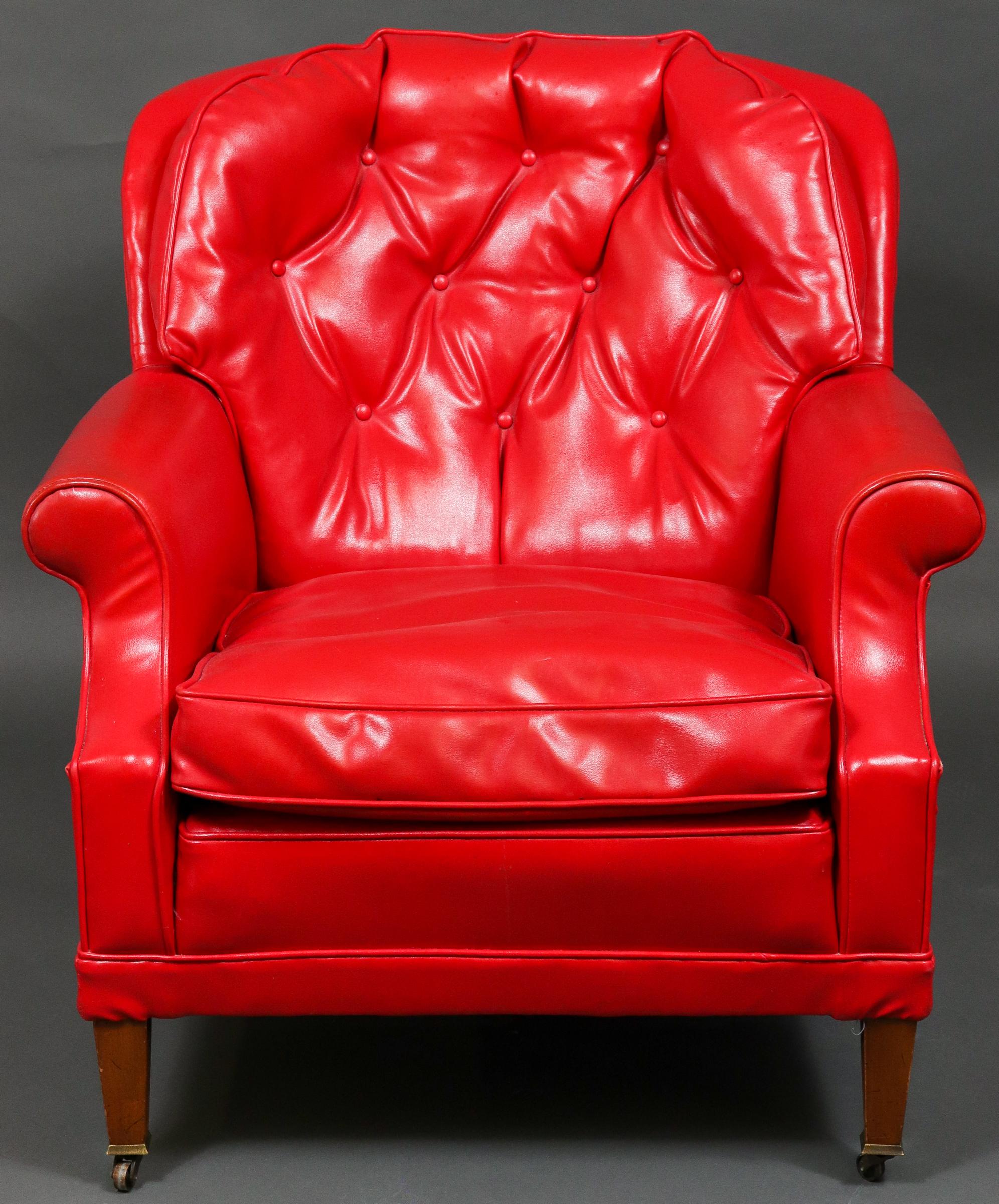 Traditional tufted red vinyl club chair raised on tapering legs with casters. Measures: 32