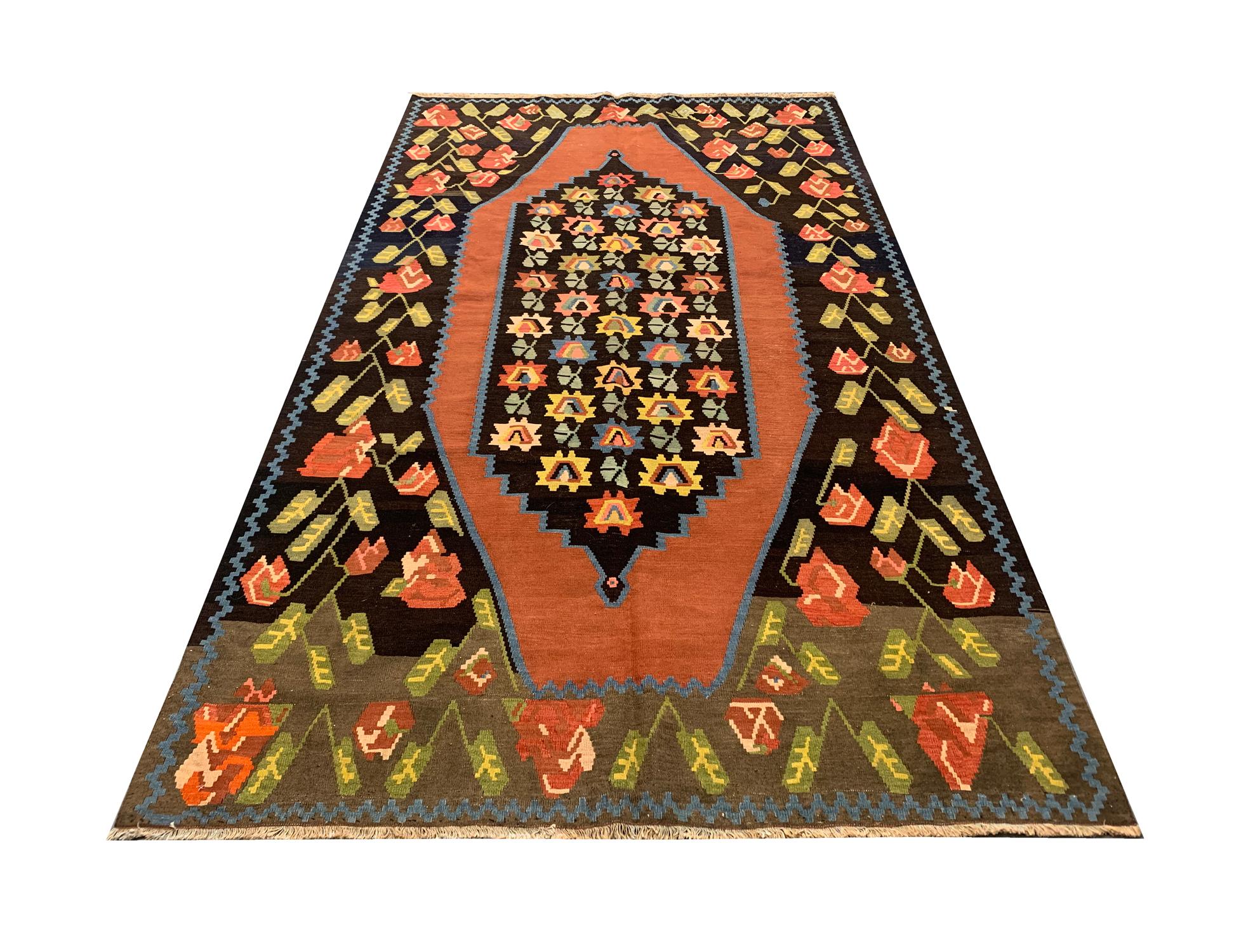 Handwoven with fine handspun wool this Karabagh Kilim is a beautiful example of antique Caucasian Kilim rugs. Brown, green, orange and yellow make up the main colors of this elegant wool rug. A dark field has been decorated with contrasting colors