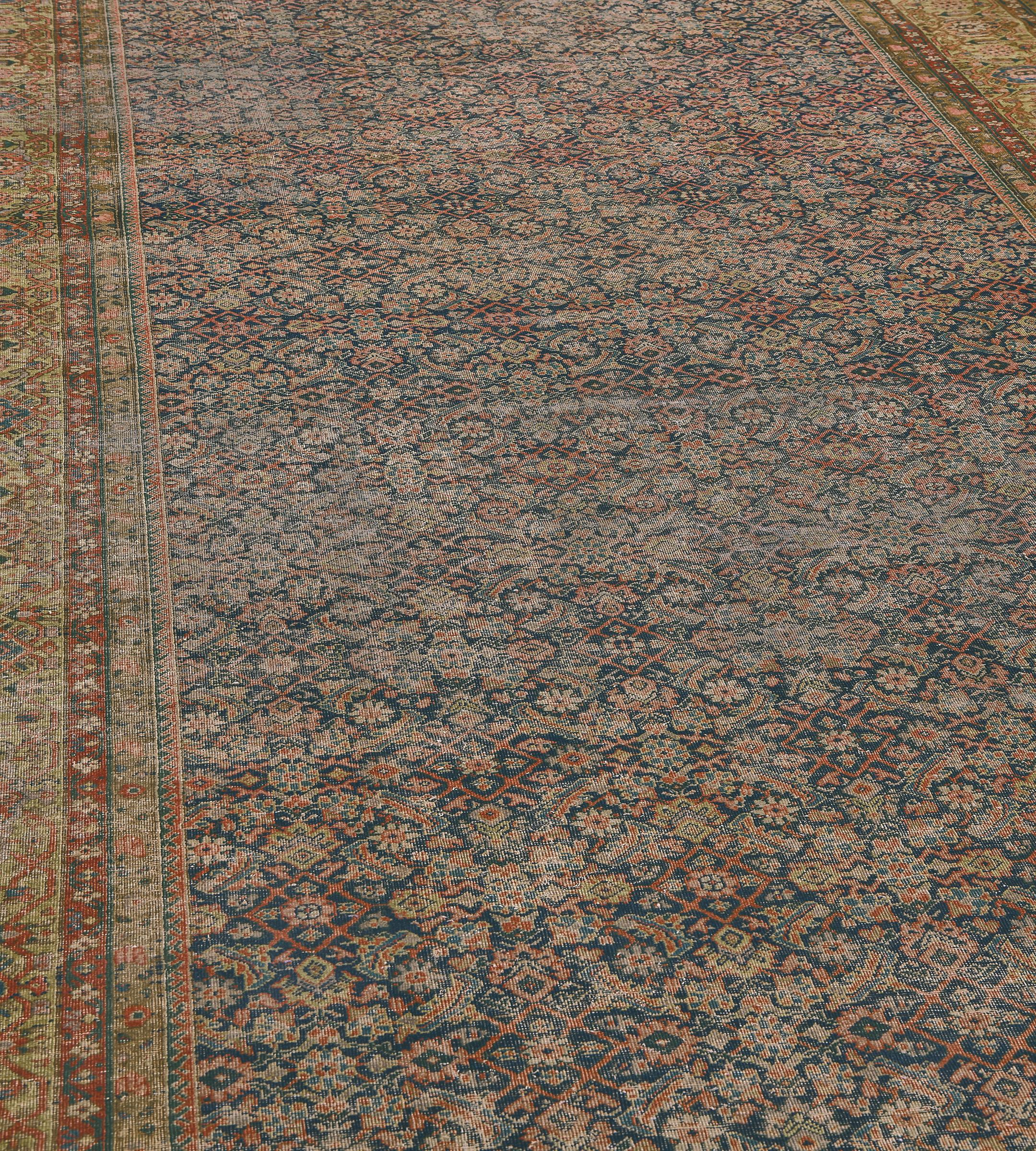 This traditional hand-woven Persian Fereghan rug has a shaded deep indigo herati field, in a faded camel turtle-palmette border, between a profusion of delicate laced floral vine stripes.