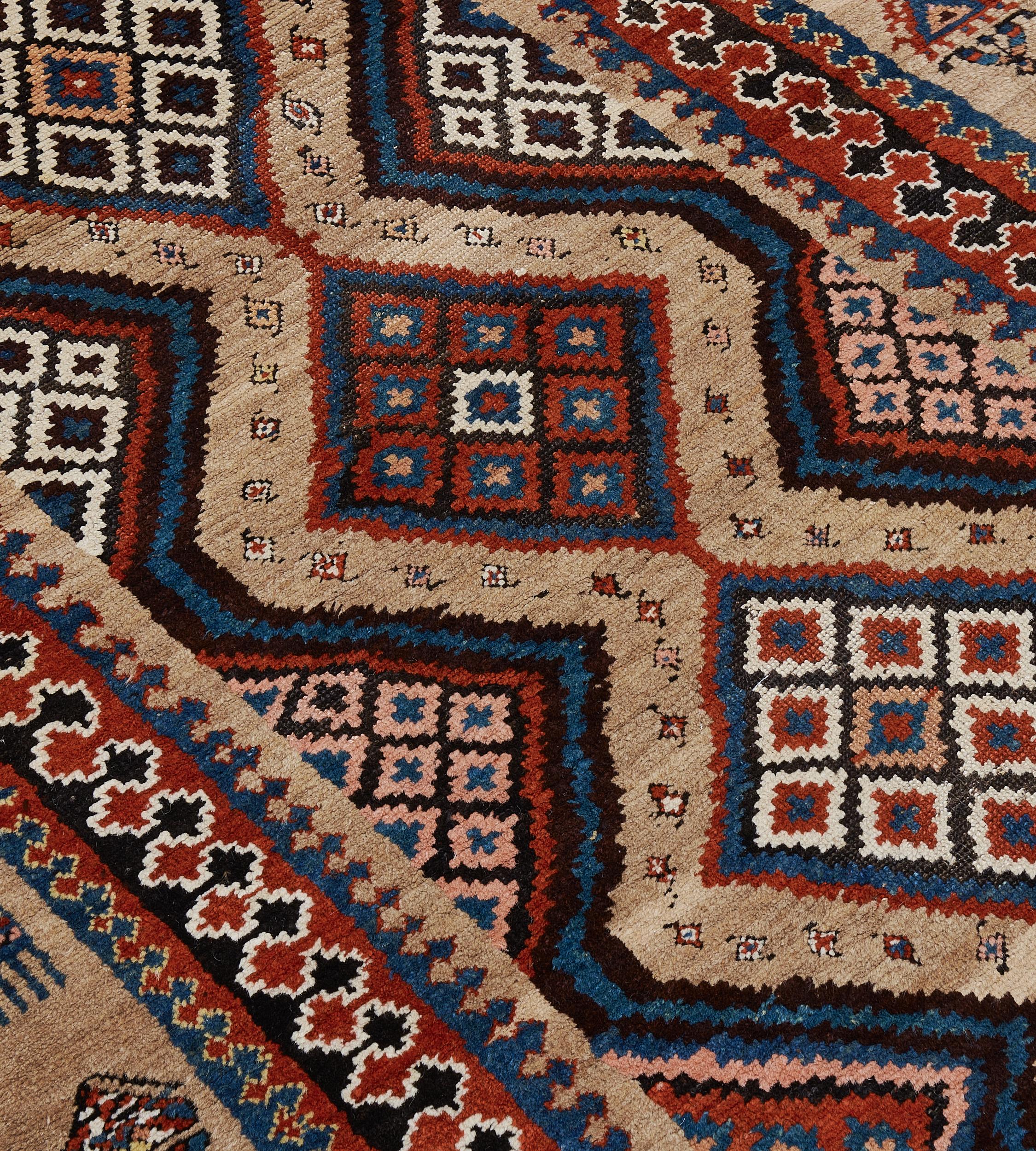 Ce tapis persan Serab traditionnel tissé à la main présente un champ tabac clair nuancé parsemé de losanges et une seule rangée de losanges polychromes entourant une autre géométrie, avec des écoinçons similaires, dans de délicates rayures à motif