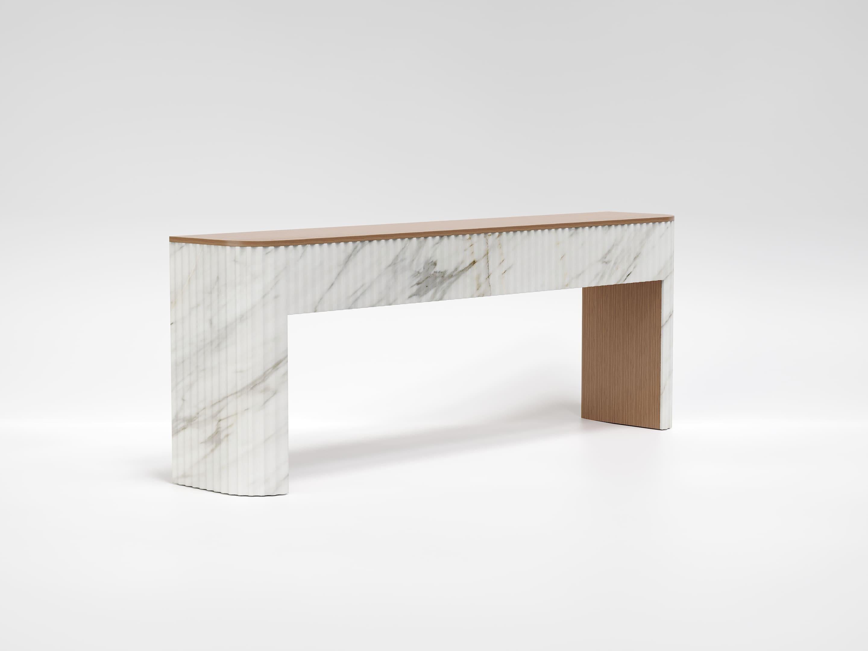A refined and elegant piece of furniture that combines the purity of premium Calacatta Gold marble with the warmth of white oak.
The structure stands out for its essential and sculptural design, enriched by vertical grooves on the marble base, a