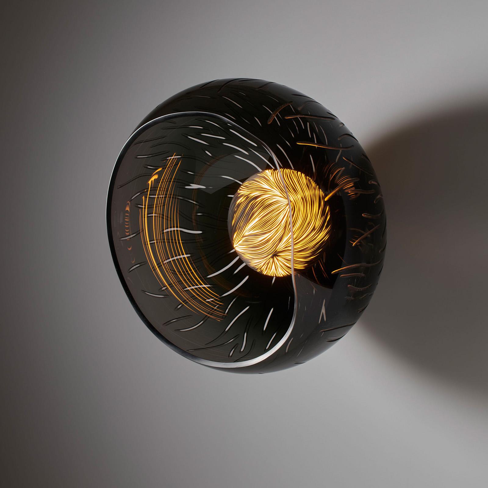 Tramonto Sul mare, a black engraved glass light with a captivating black and white ceramic core, serves as a testament to the harmonious fusion of artistry and functionality. Drawing inspiration from the breath-taking reflection of sunlight dancing