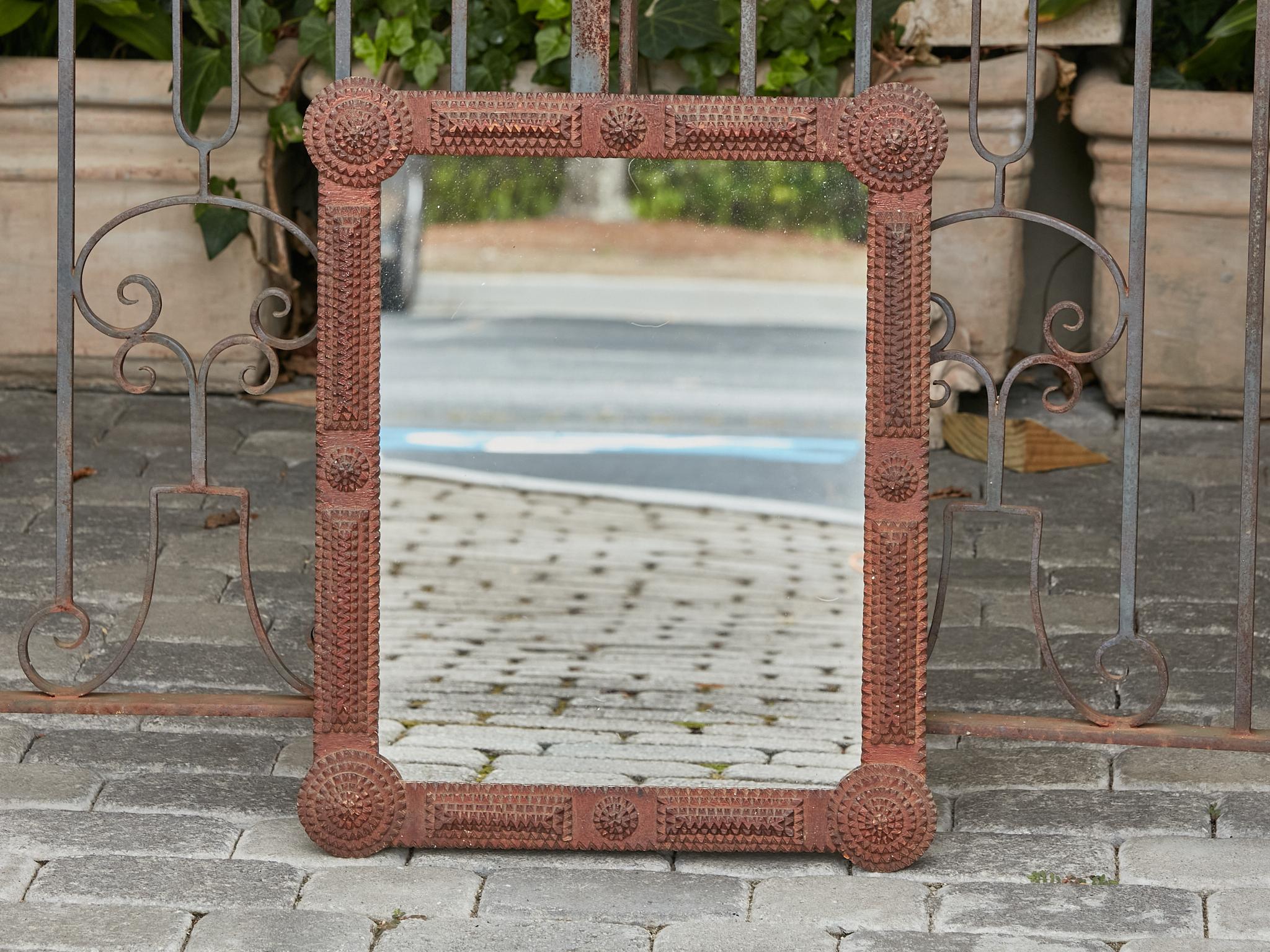 A French Tramp Art hand-carved wooden mirror from circa 1900 with circular protruding raised medallions in the corners. This French Tramp Art hand-carved wooden mirror, dating back to circa 1900, is a remarkable example of folk artistry and detailed