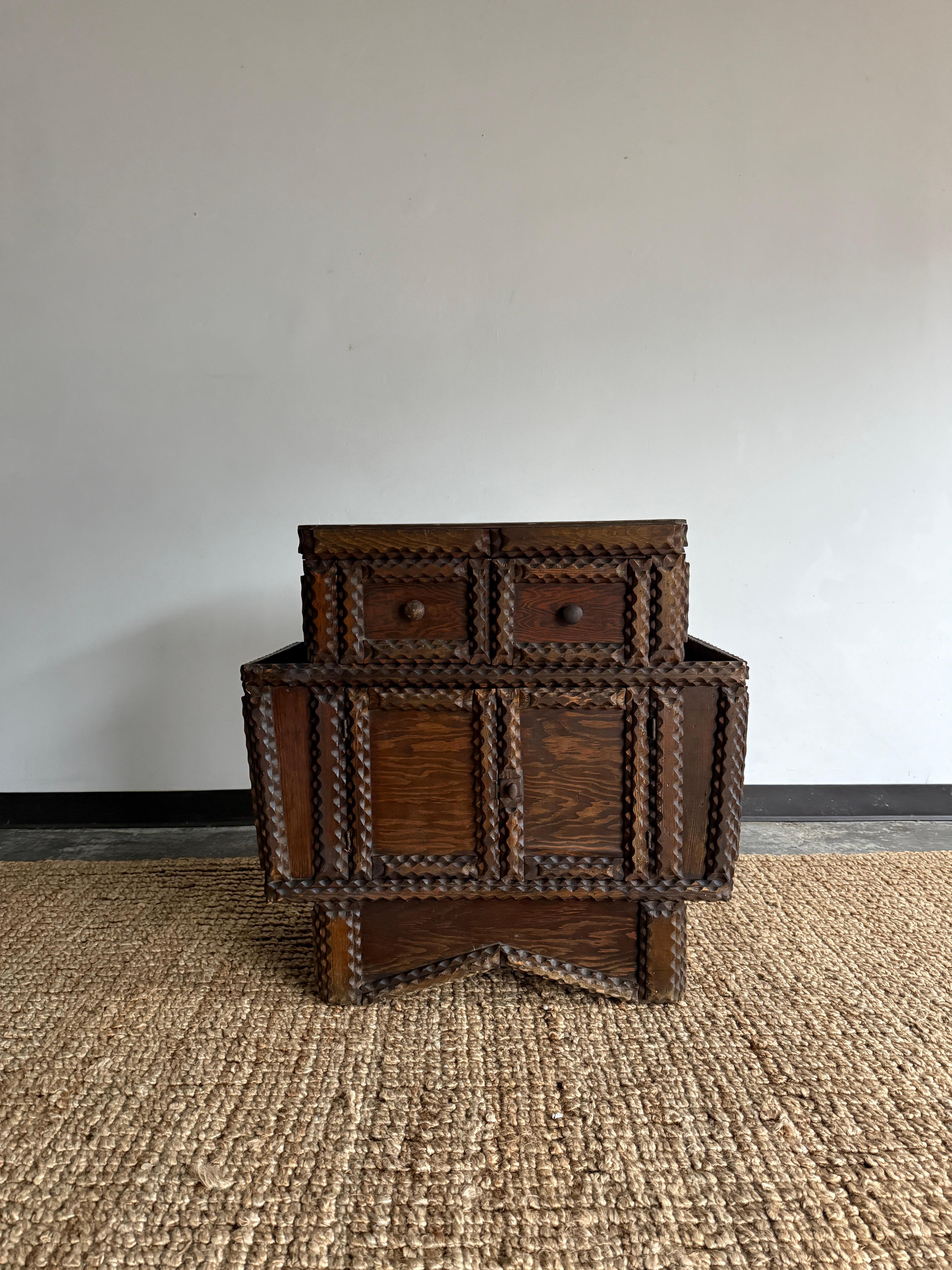 tramp art cabinet featuring deep storage pockets on each side, a compartment on the front with two doors, and two drawers at the front. In excellent condition for age. A pieces that would incorporate seamlessly with a variety of decor styles. 