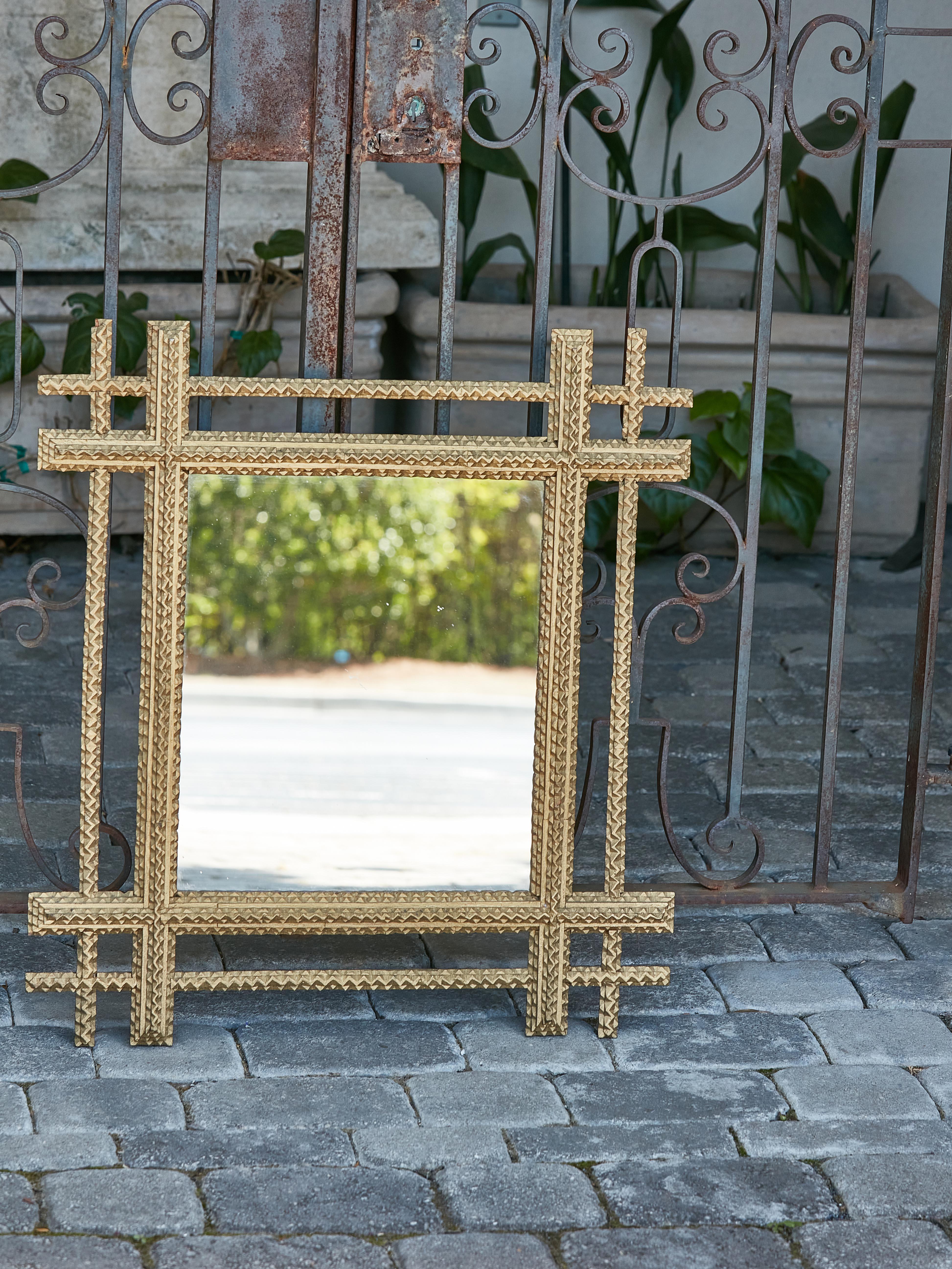 An unusual Tramp Art mirror from circa 1920 with hand-carved gilded frame and intersecting corners. Step into an opulent realm of craftsmanship with this spellbinding Tramp Art mirror, circa 1920, where every meticulous hand-carved detail beckons