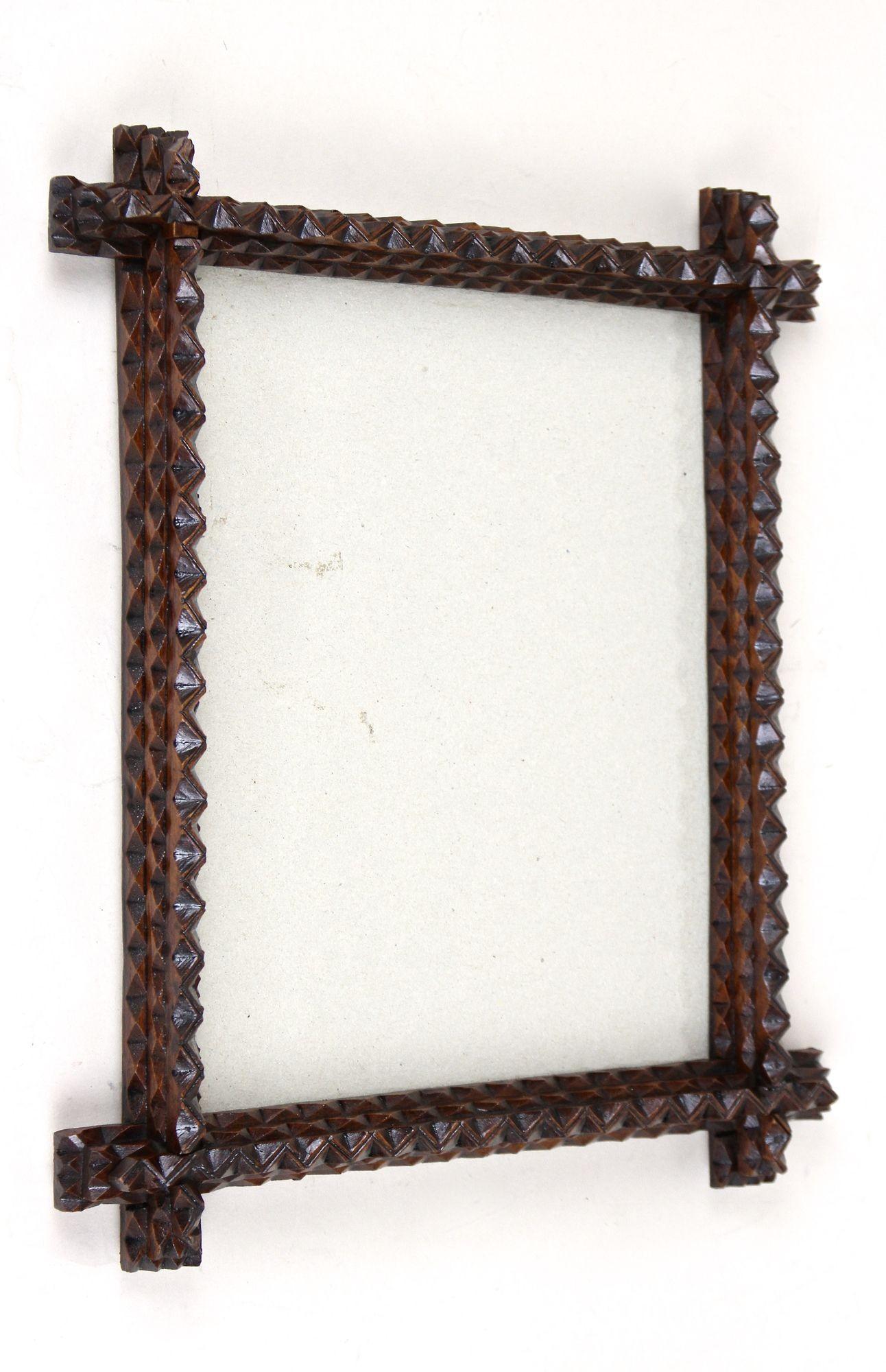 Decorative Tramp Art photo frame from the period in Austria around 1880. Elaborately hand carved out of bass wood this rustic photo frame comes with a lovely design which is reinforced by the dark brown stained surface. Holding the still original