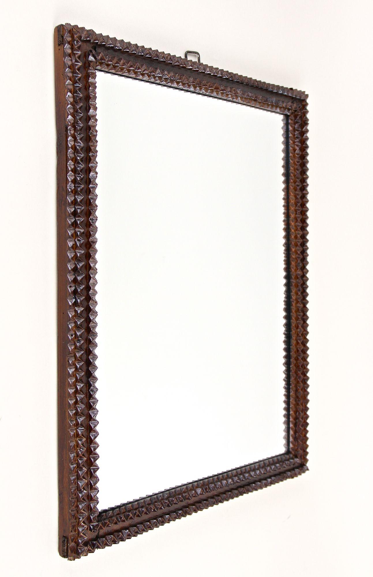 Beautiful late 19th century rustic Tramp Art wall mirror coming out of Austria from the period around 1870. The lovely brown stained, hand carved basswood frame shows beautiful chip carvings - a technique which confers this very popular kind of