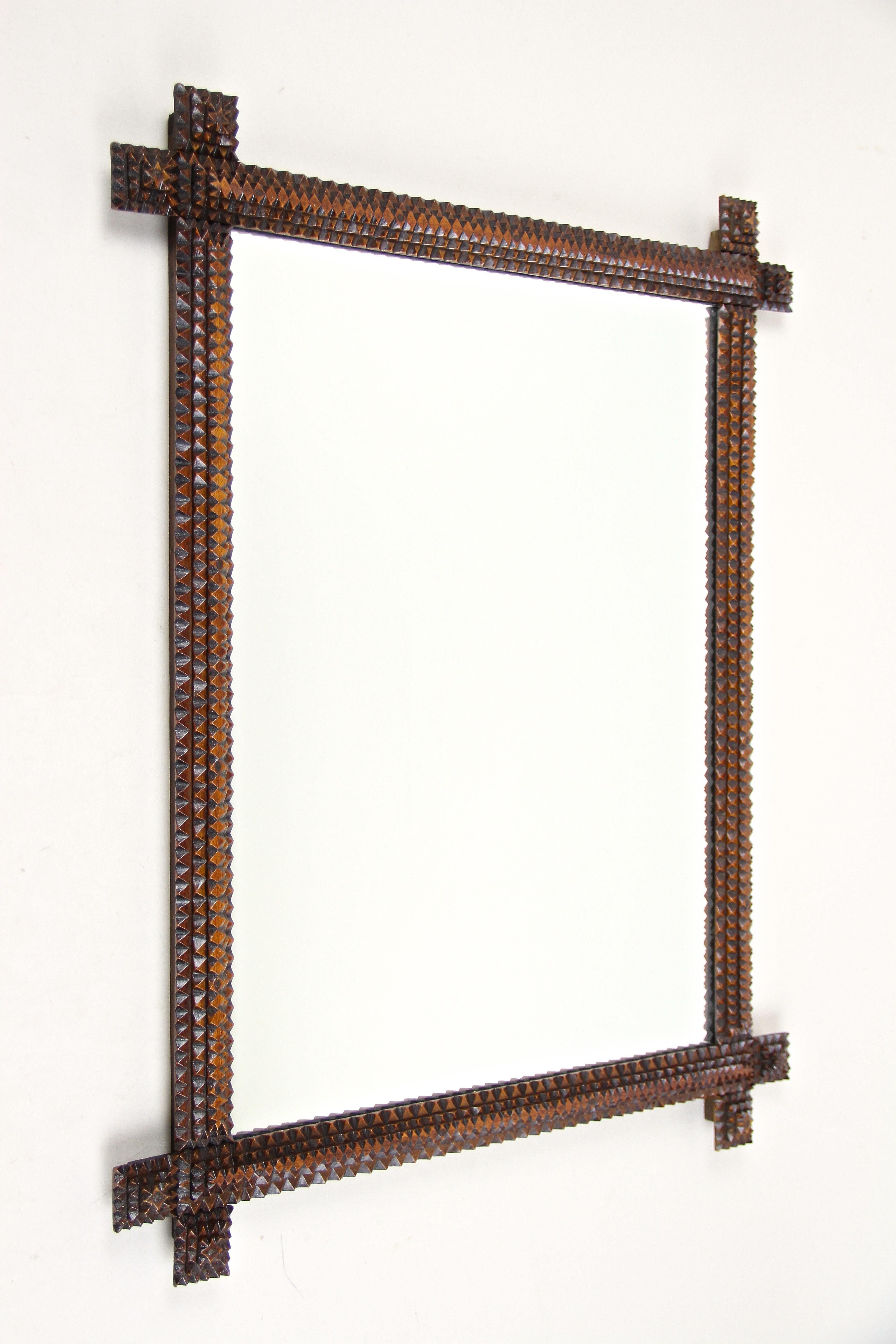 Exceptional rustic Tramp Art wall mirror from the late 19th century in Austria. This remarkable hand carved wooden mirror has been artfully handcrafted out of basswood around 1880 and comes with a delightful brown varnished surface. Beside the