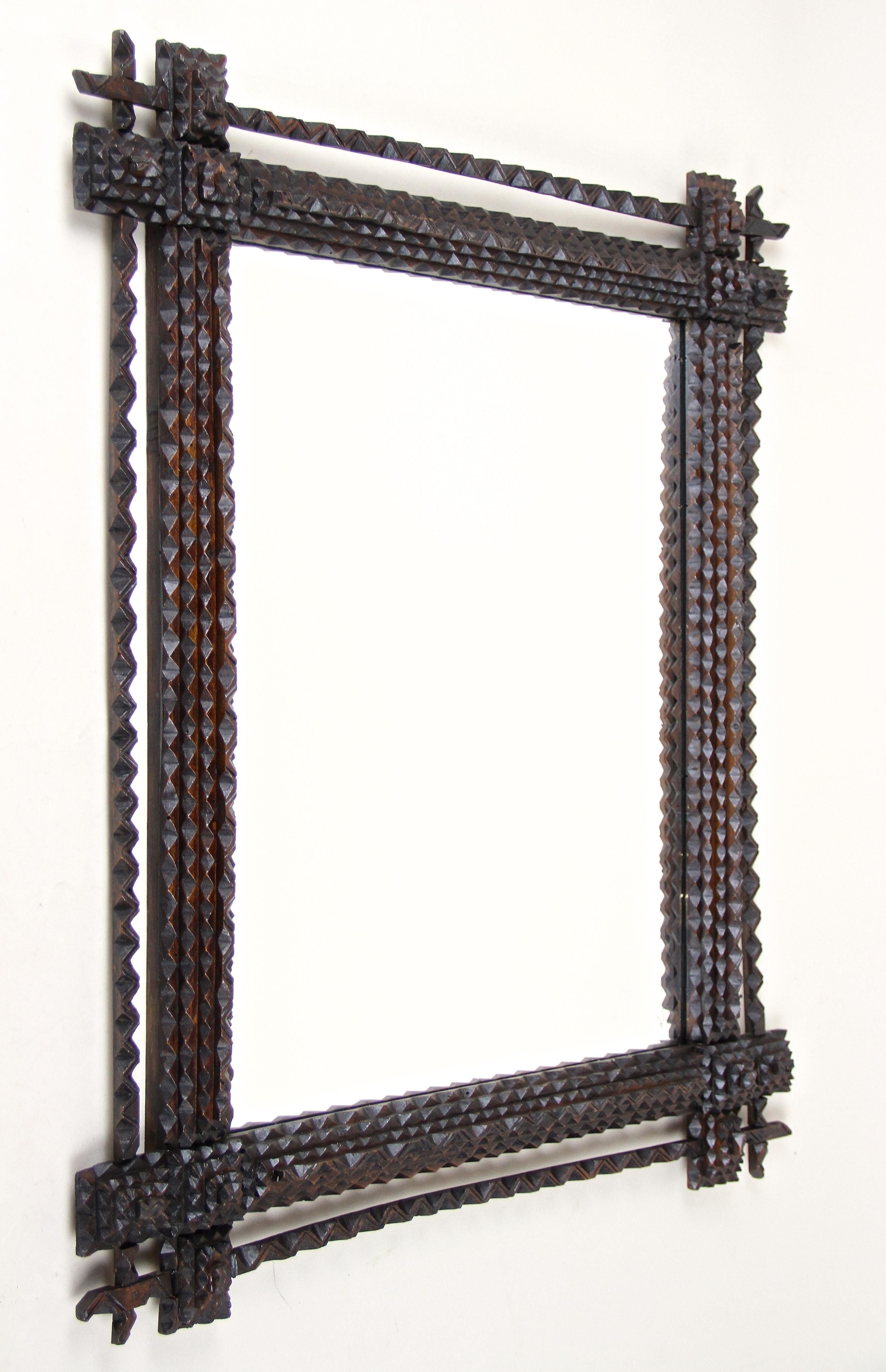 Ungewöhnlicher Tramp-Art-Spiegel aus dem späten 19. Jahrhundert in Österreich. Dieser rustikale Spiegel wurde um 1870 aufwändig aus Lindenholz geschnitzt und ist mit seiner dunkelbraun gebeizten Oberfläche in einem hervorragenden Originalzustand.