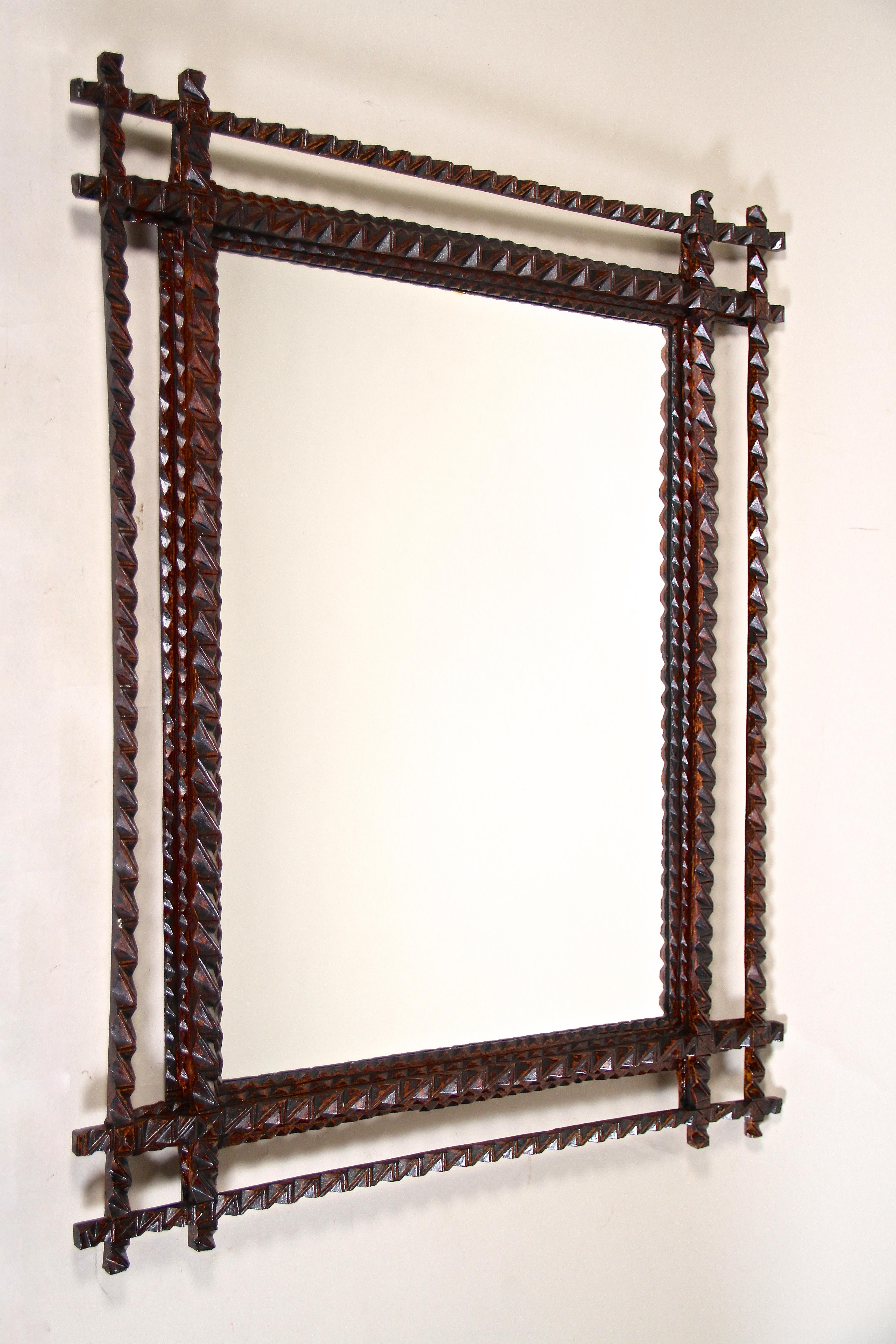 Fantastic Tramp Art Wall Mirror from the late 19th century in Austria around 1880. This rustic mirror has been elaborately hand carved out of basswood and comes with a dark brown stained surface in perfect original condition. Highlighted by a