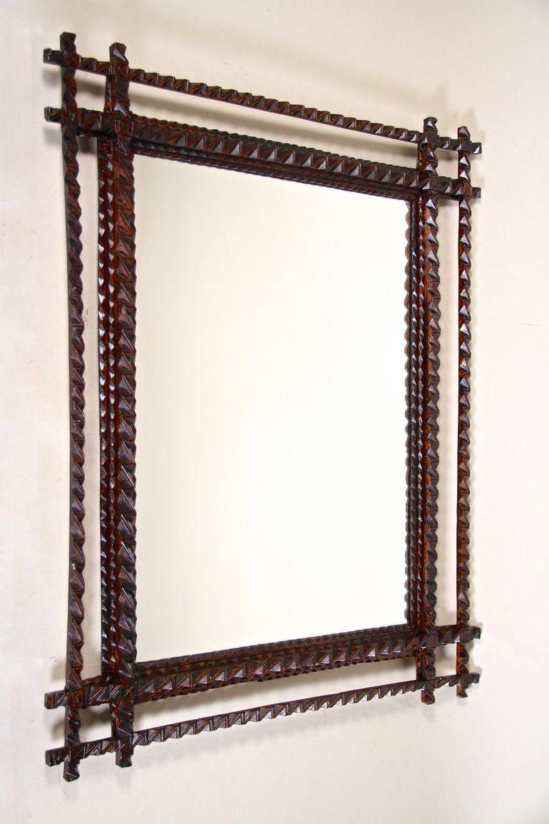 Fantastico specchio da parete Tramp Art della fine del XIX secolo in Austria, intorno al 1880. Questo specchio rustico è stato elaborato a mano in legno di tiglio e presenta una superficie macchiata di marrone scuro in perfette condizioni originali.