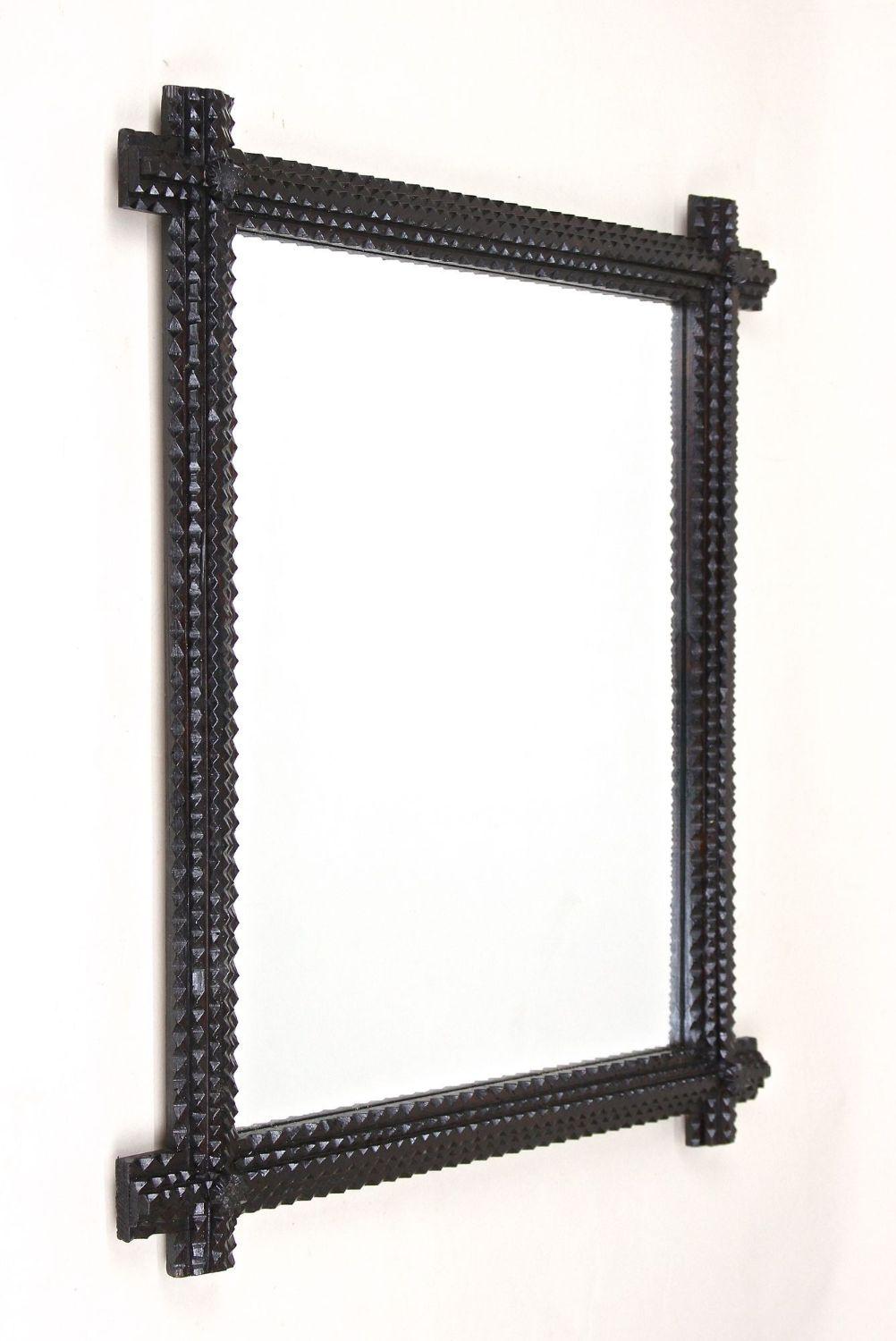 Delightful rustic Tramp Art wall mirror from the late 19th century in Austria around 1880. Elaborately hand carved out of basswood this over 140 year old Tramp Art mirror comes with a dark brown, almost black looking surface sealed with a nice semi