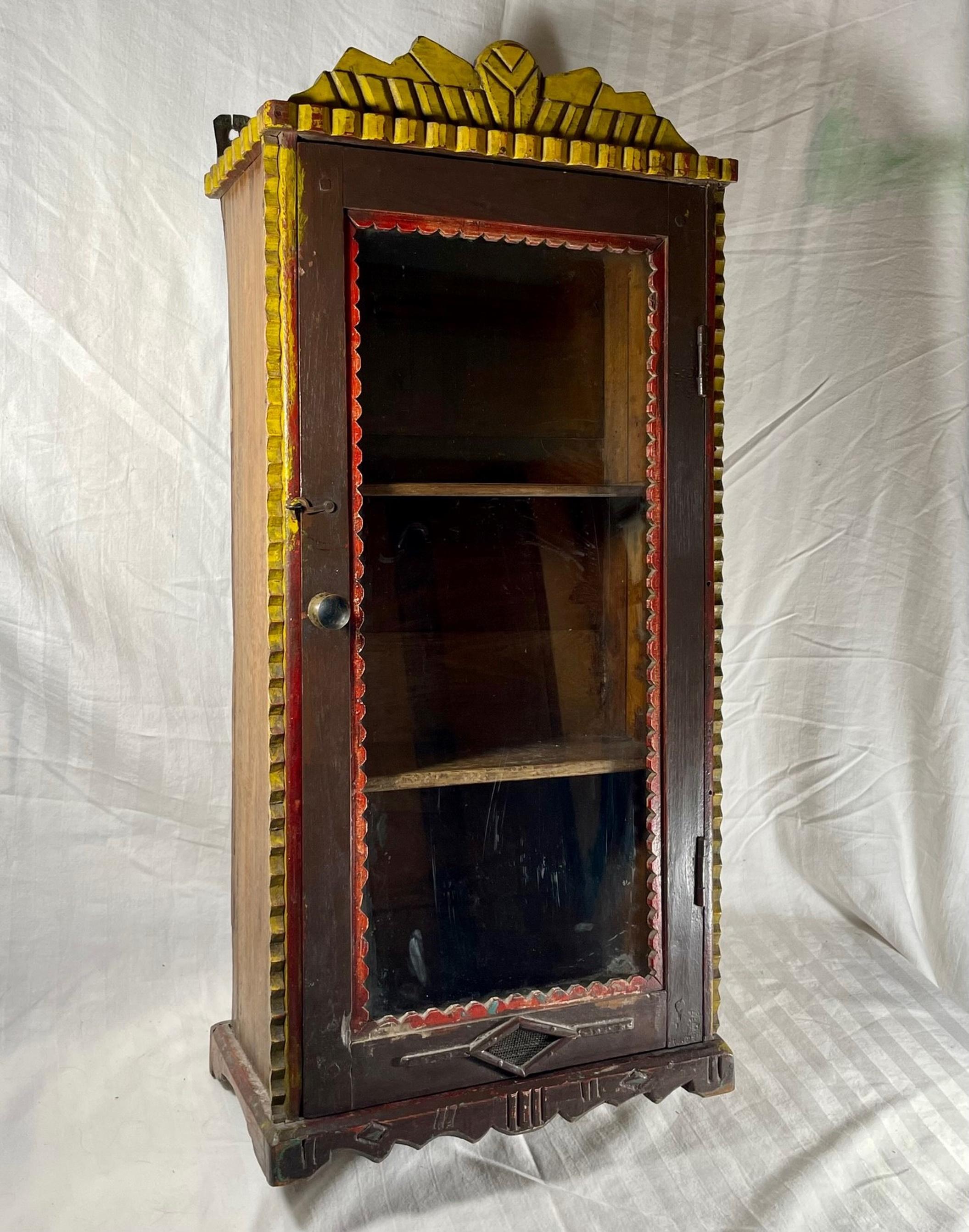 Antique tramp art wall hanging cabinet hand carved and painted ca 1880

The Tramp Art wall cabinet has great details of geometric hand cut scrap
wood and rich notch carvings. It’s rustic charm is amplified with the original
painted decorations.