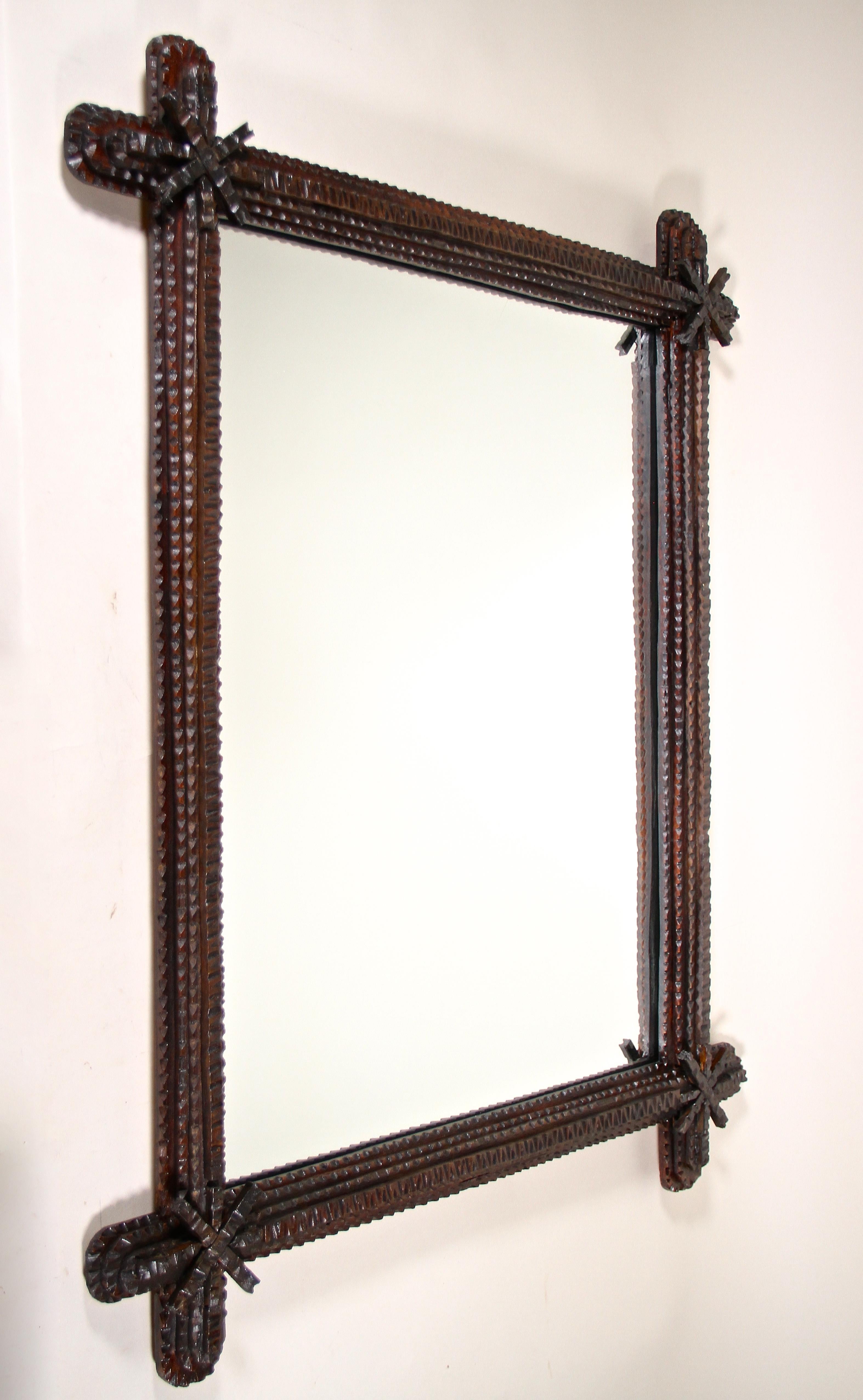 Fantastic rustic Tramp Art Mirror from the late 19th century in Austria. Hand carved around 1870 out of basswood in a very artful way, this unique rural wall mirror impresses with lovely chip carvings. The protruding, rounded corners are