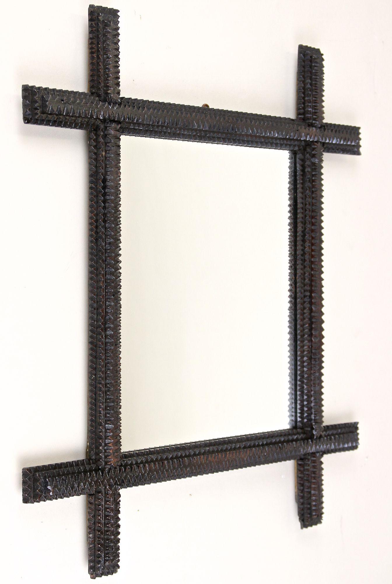 Decorative rustic Tramp Art wall mirror from the late 19th century around 1870 in Austria. Elaborately hand carved out of fine basswood, the solid frame impresses with its artfully pyramidal notch cut embedded in a simple but still spectacular