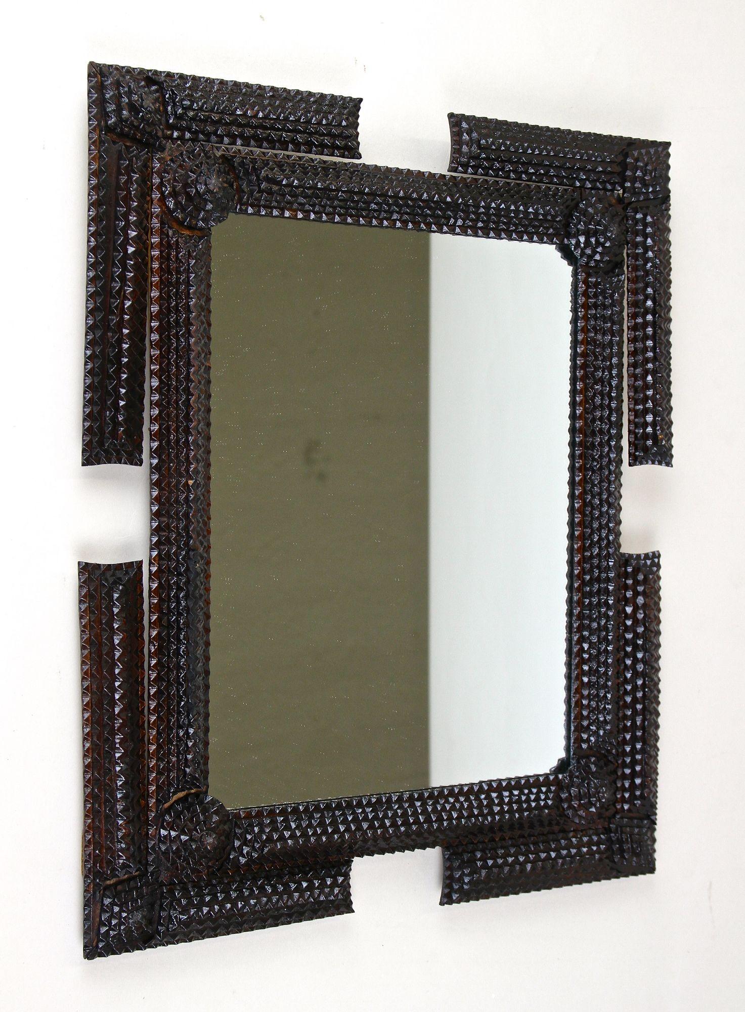 Exceptional rustic Tramp Art wall mirror from the late 19th century period in Austria around 1870. This very elaborately hand carved mirror impresses with an outstanding designed frame which is adorned by elaborately worked chip carvings. The