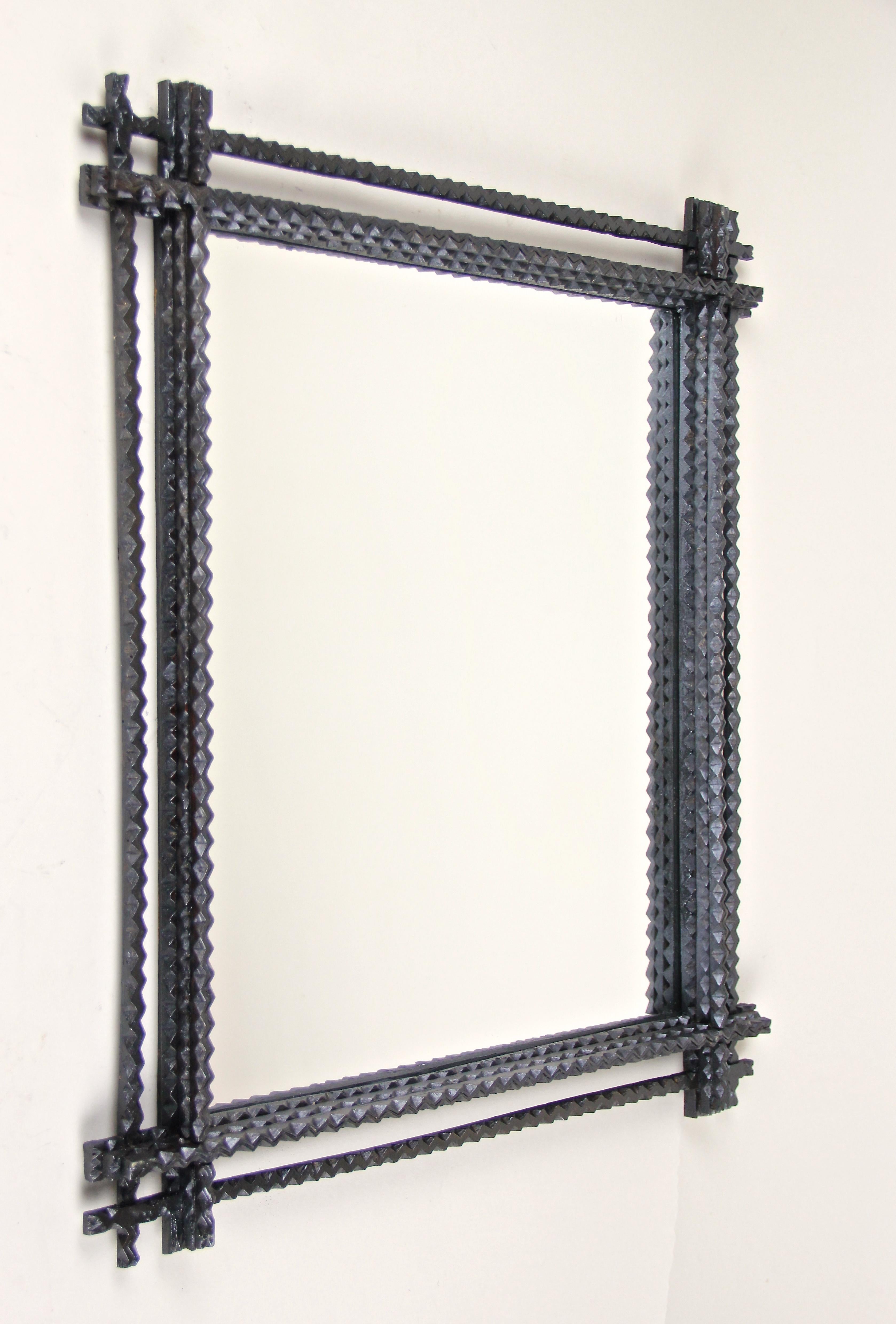 Gorgeous hand carved tramp art wall mirror from Austria, circa 1880. This rustic wall mirror has been effort fully hand carved out of basswood and comes with a dark brown almost black surface. Framed by additional slim bars on the outside, the