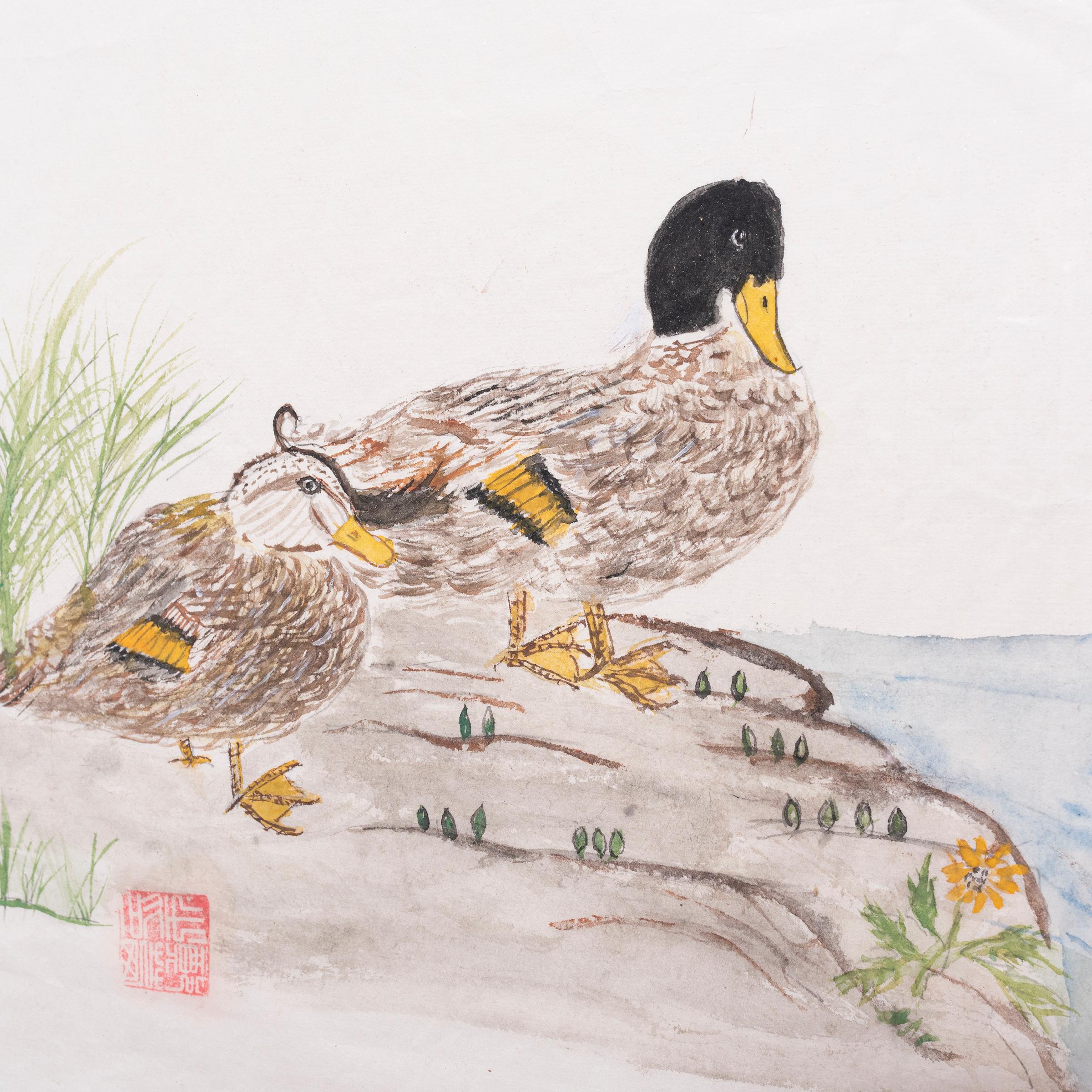 Dieses bezaubernde Aquarell ist im Stil traditioneller Tintenkalligraphie gestaltet und zeigt zwei Enten, die sich an einem Flussufer ausruhen. Das felsige Gelände ist mit hohem Gras und grünen Trieben übersät, und das ruhige Wasser plätschert an