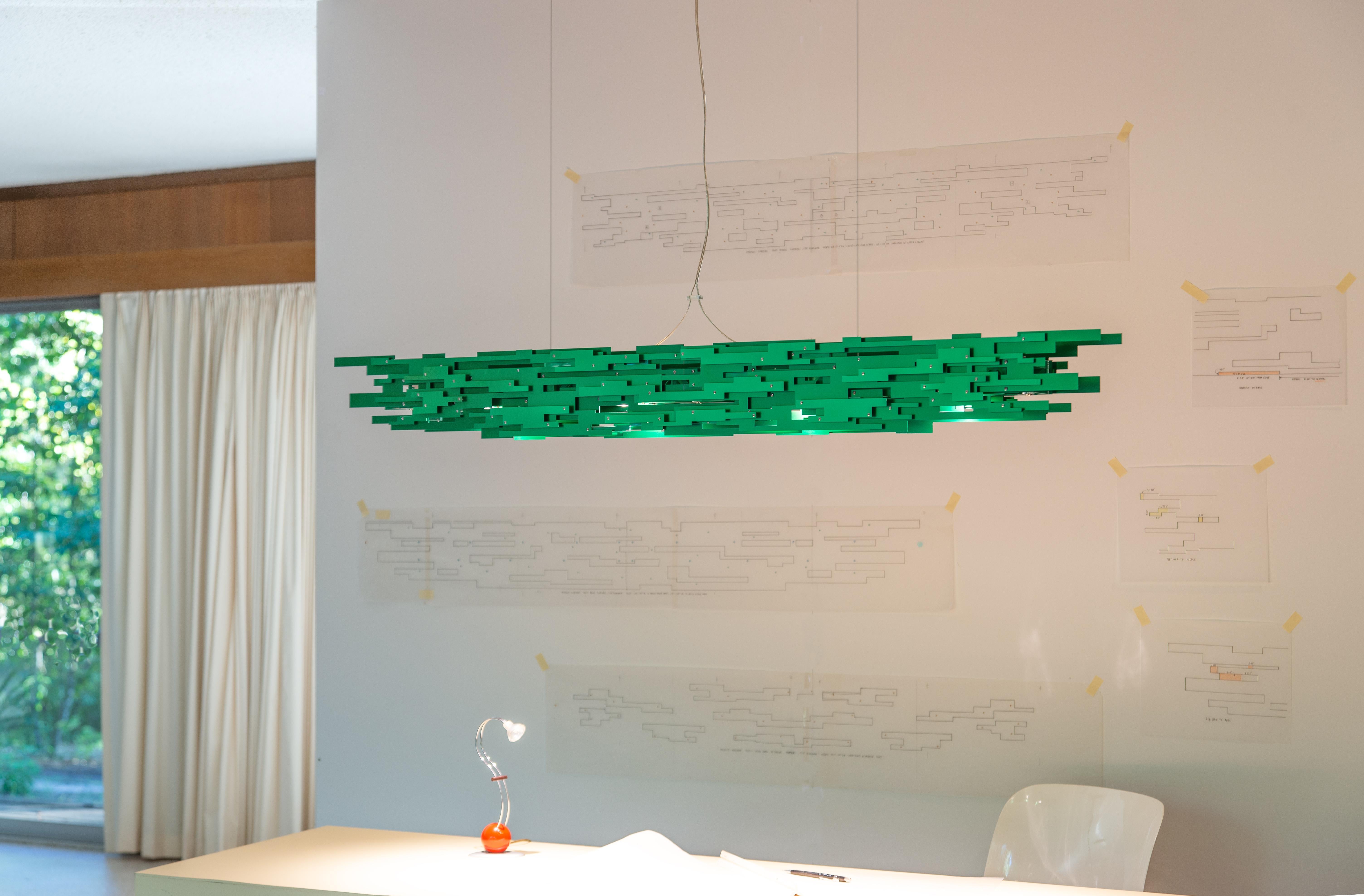 Transit is a handmade aluminum linear chandelier providing warm direct LED illumination when suspended over a dining table, kitchen island or conference table. Both sides of the Transit are assembled from three rectilinear surfaces on three separate
