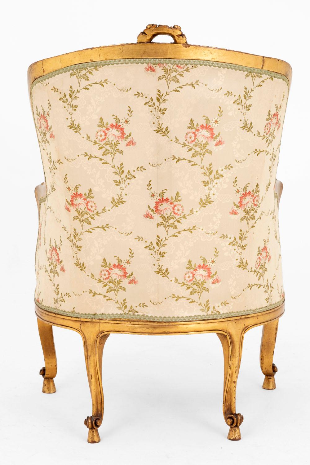 Transition style bergere in carved and giltwood with foliage and interlacing decor. Four cabriole legs ending in scrolls and standing on square bases. The seat profile is slightly bulged and covered with a nice champagne fabric decorated of red and