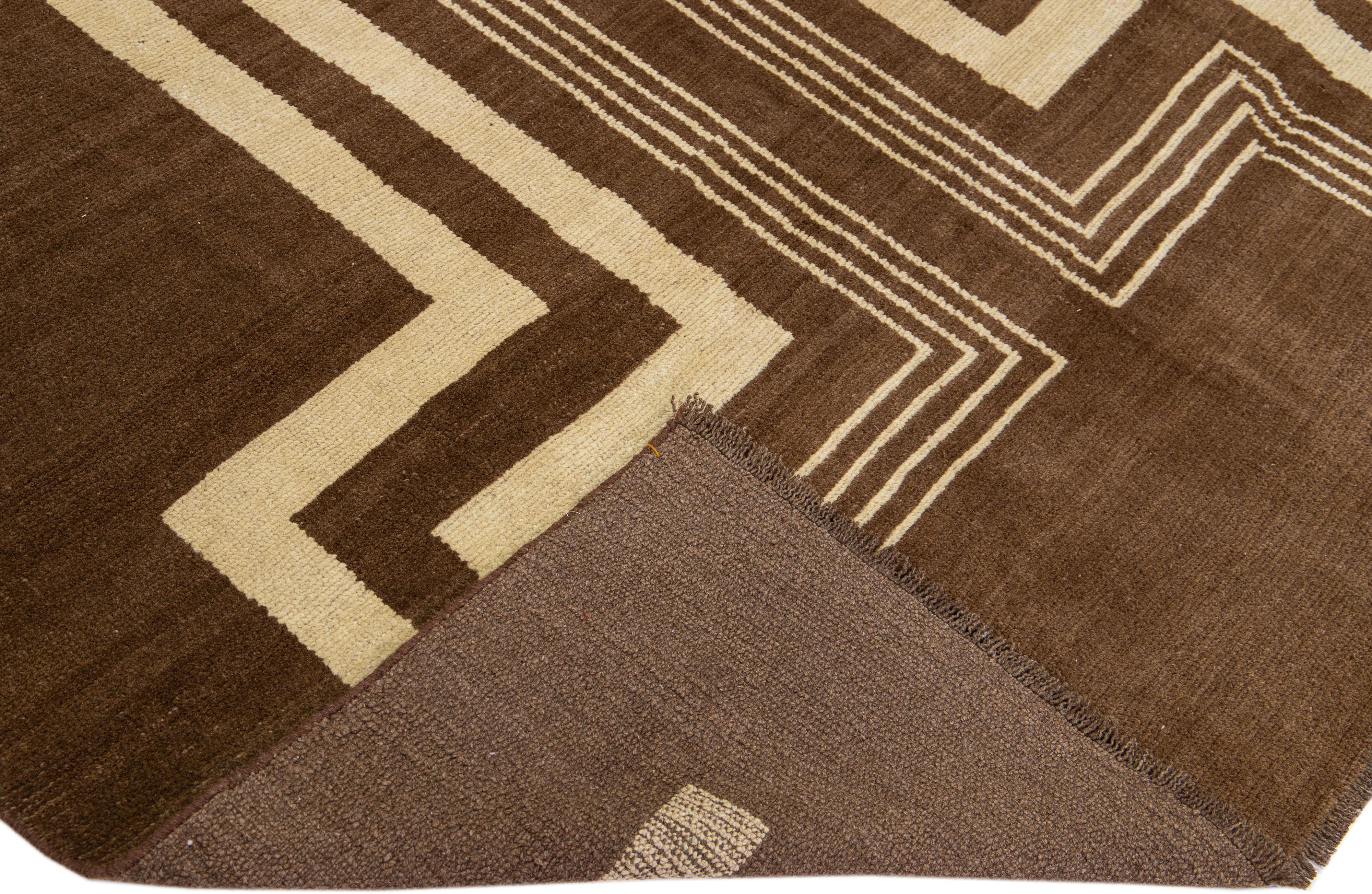 This Beautiful Modern Art Deco handmade wool rug makes part of our Northwest collection and features a brown color field and beige accents in a gorgeous geometric tribal design.

This rug measures: 7'4