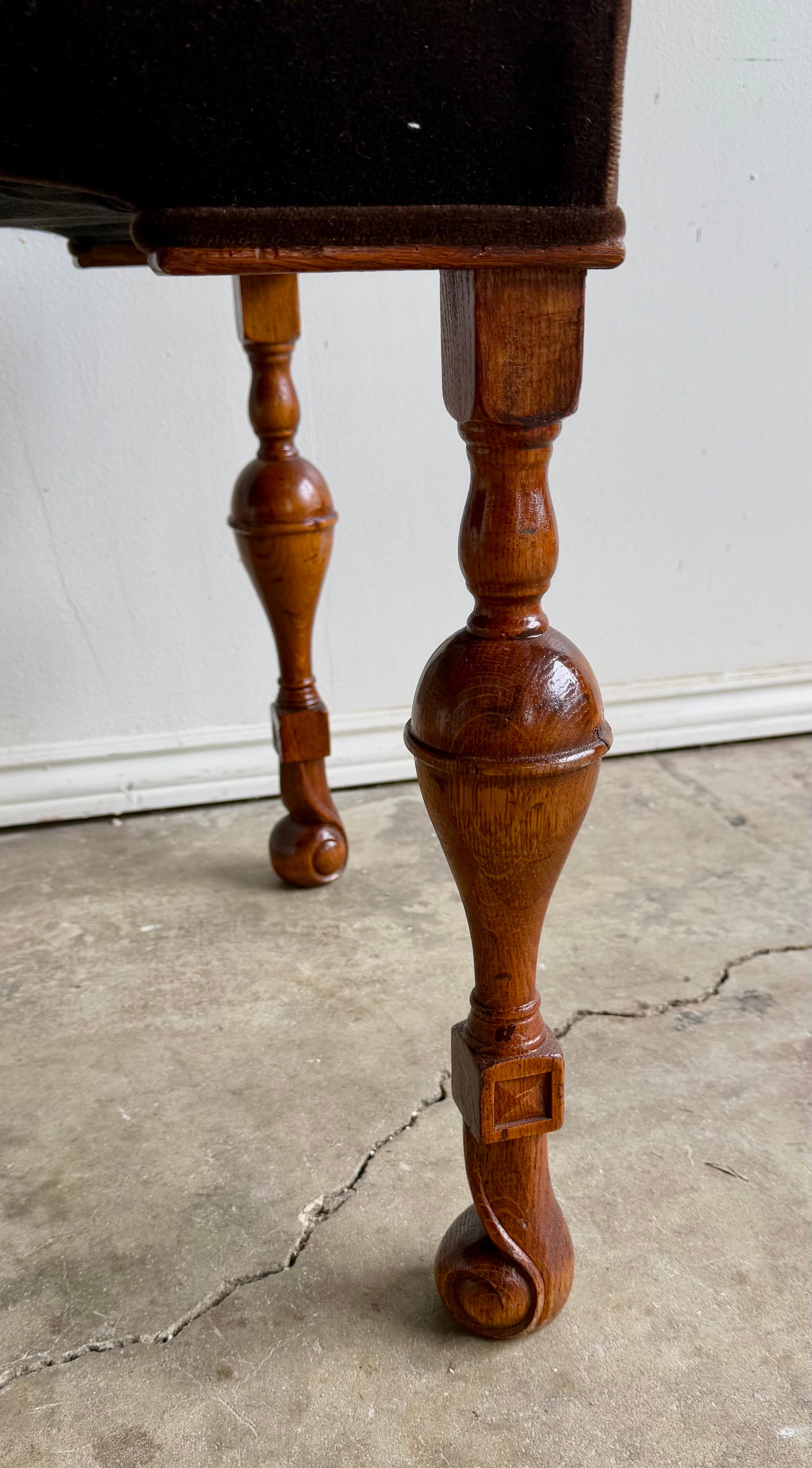 Banc en bois de forme rectangulaire recouvert d'un riche tissu de couleur chocolat foncé.  Le banc est doté de pieds en bois tournés de manière complexe et d'une finition polie.  Les pieds ont une forme élégante avec des détails de bulbes arrondis