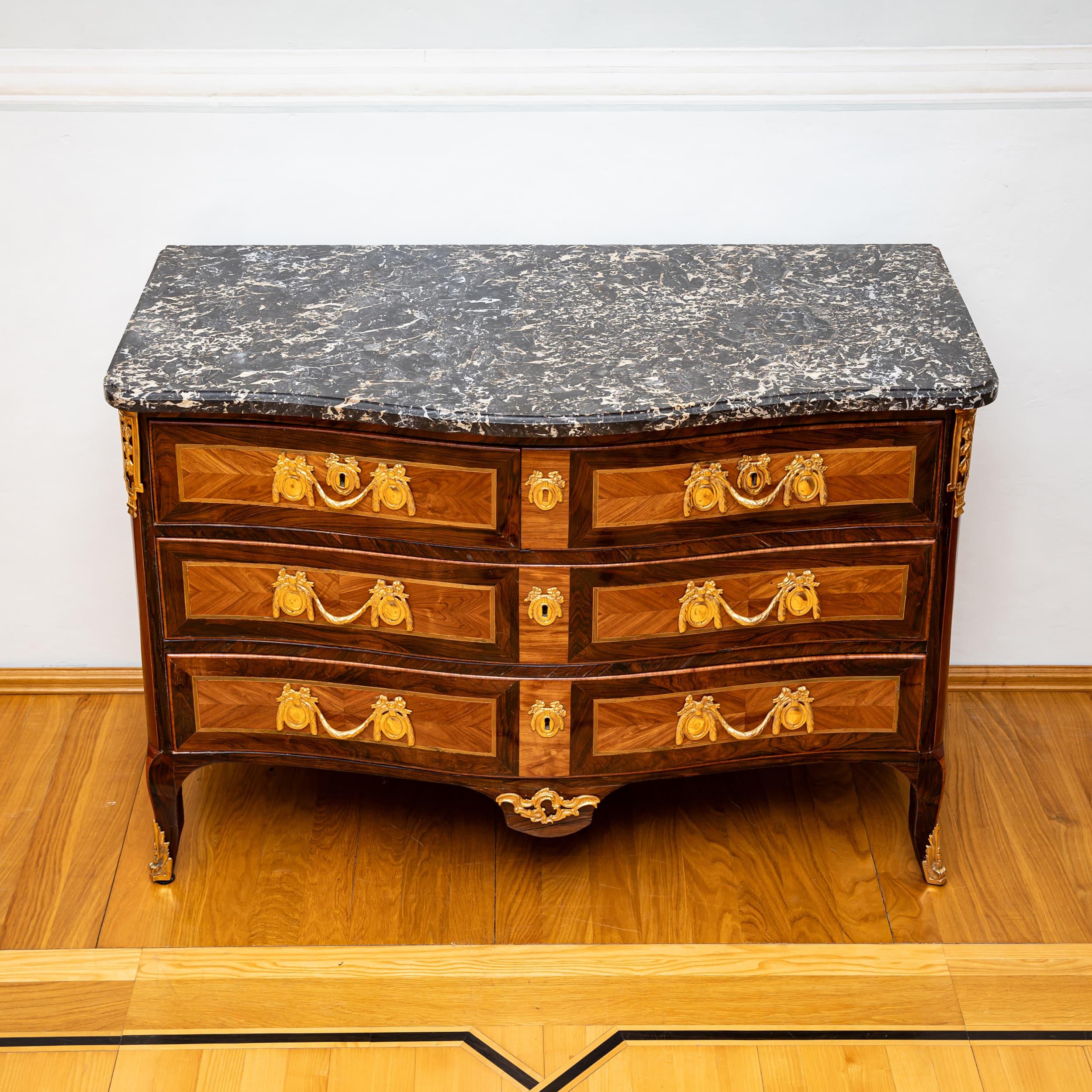French commode with three drawers in the Transitional style, combining elements of Louis XV and Louis XVI. Crafted in walnut with lighter cherrywood inlays to the front. The commode rests on gently curved, s-shaped legs, with the apron sweeping down
