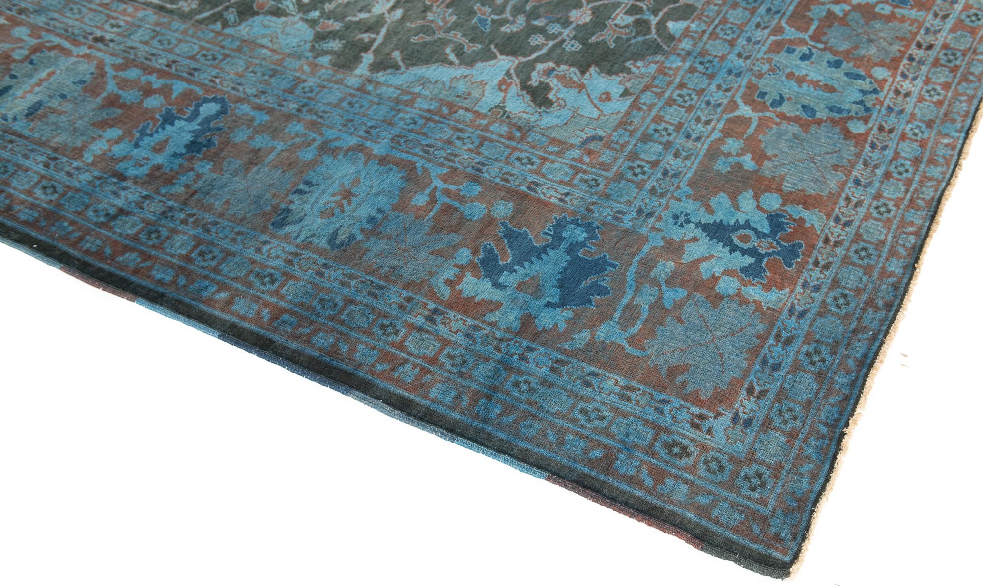 This transitional Pakistan large rug brings the old world rug design into the contemporary design world with over-dyed wool.  Finely hand knotted wool with a large field and wide border. The accent shade of red, compliments the all over blue color. 