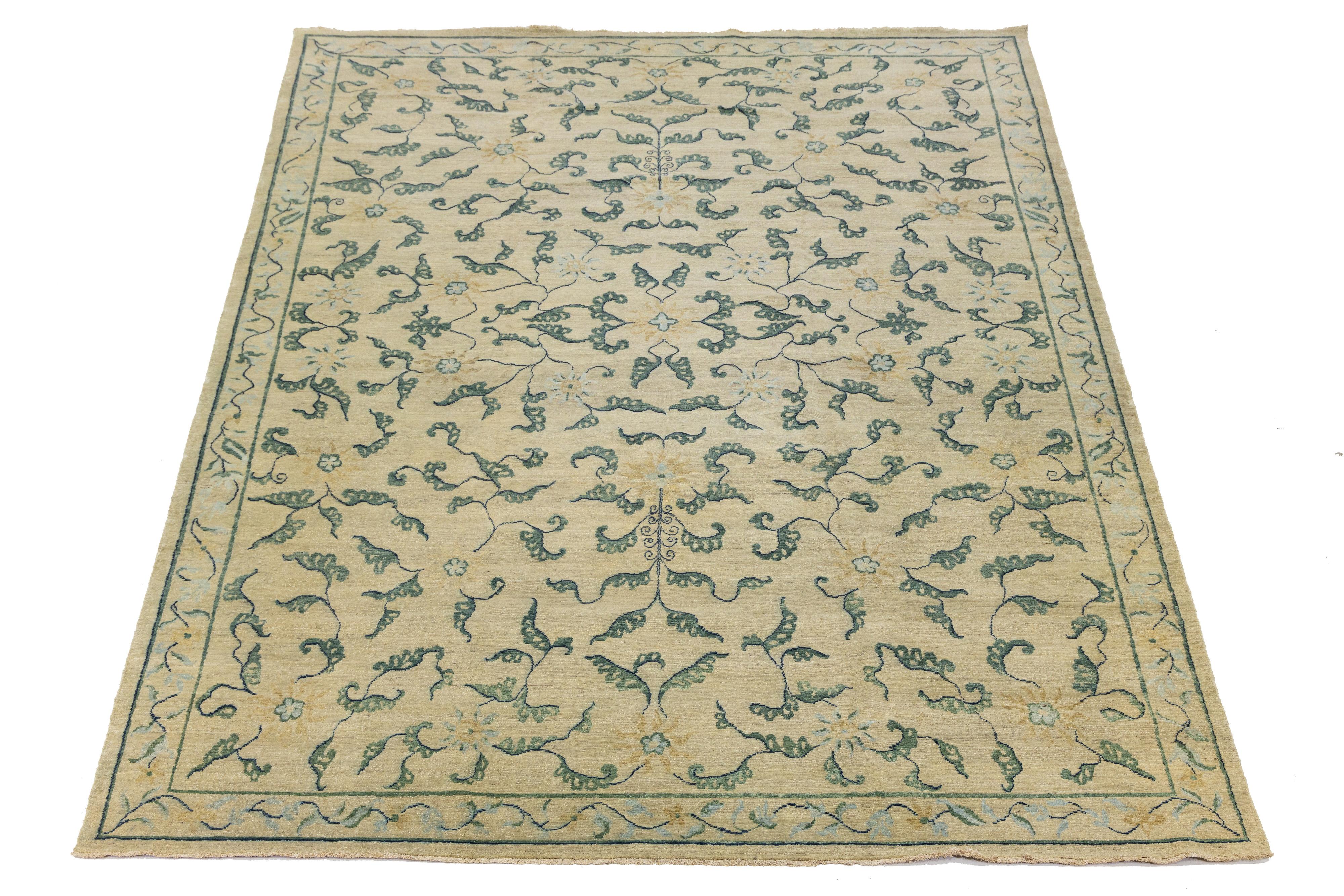 Esta alfombra contemporánea anudada a mano muestra un impresionante diseño floral con una combinación de colores verdes. Fabricado con lana de alta calidad, presenta un fondo beige que resalta maravillosamente el intrincado dibujo. La rica paleta de
