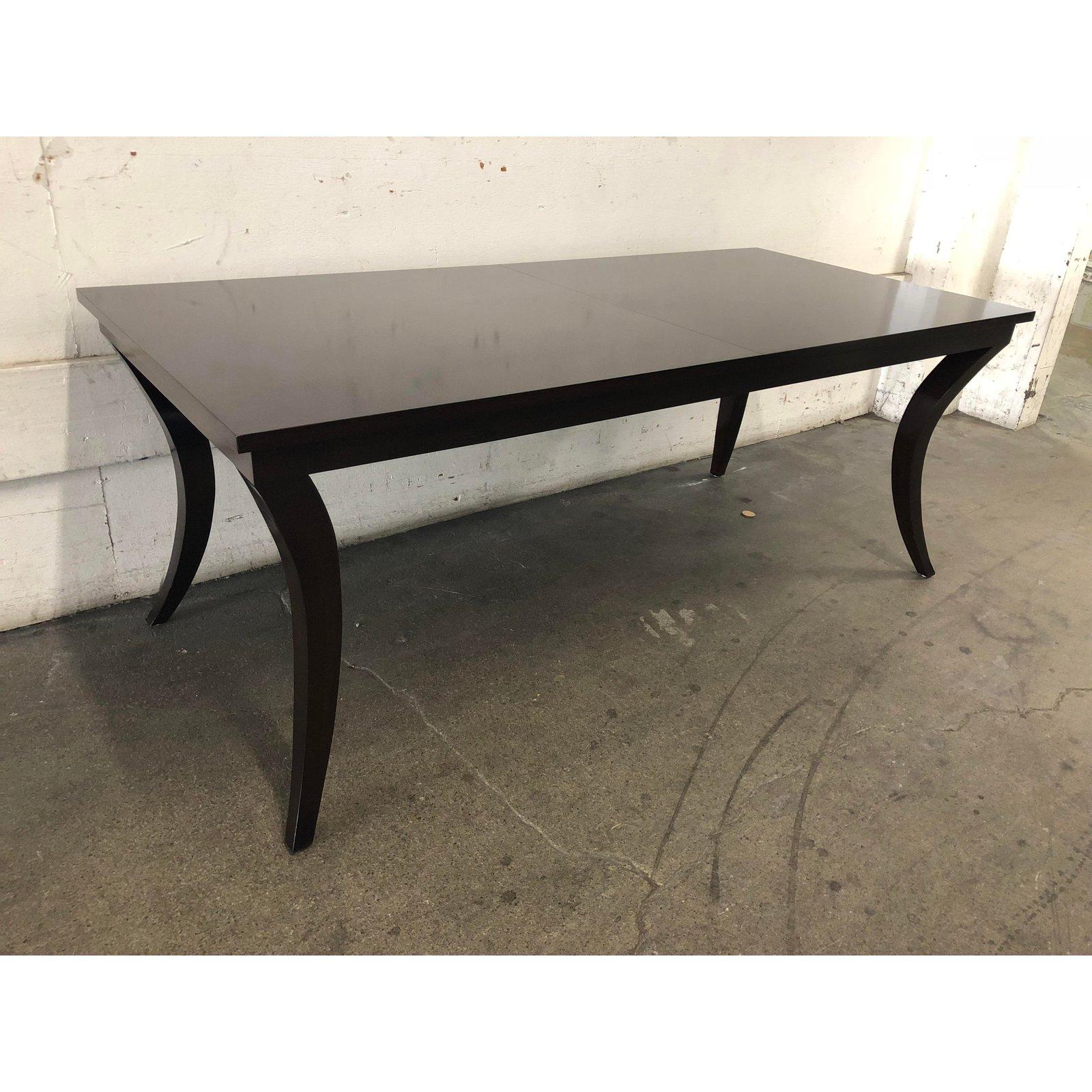 A contemporary dining table in a deep dark brown finish. The unique legs are a contemporary turn on traditional sabre legs, tapered and turned inwards toward each other at a 45 degree angle. Like the slender arched legs of the gazelle, these table