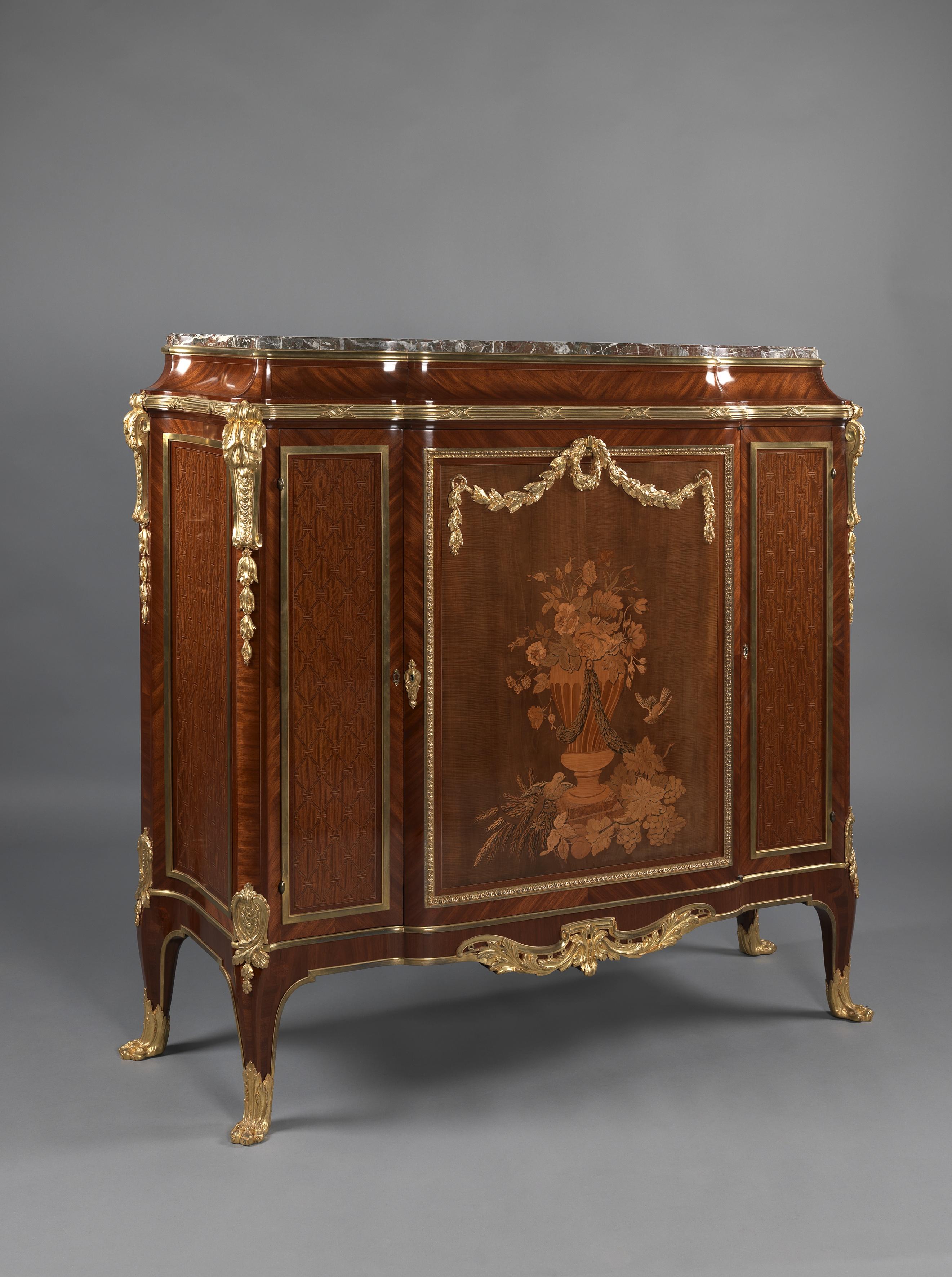 A fine Transitional style Marquetry-inlaid side cabinet with a Rouge de rance marble-top.

French, dated 1912. 

Marked ‘SJ' and dated 1912 in the marquetry. 

This impressive side cabinet has a red and grey veined marble top above a concave