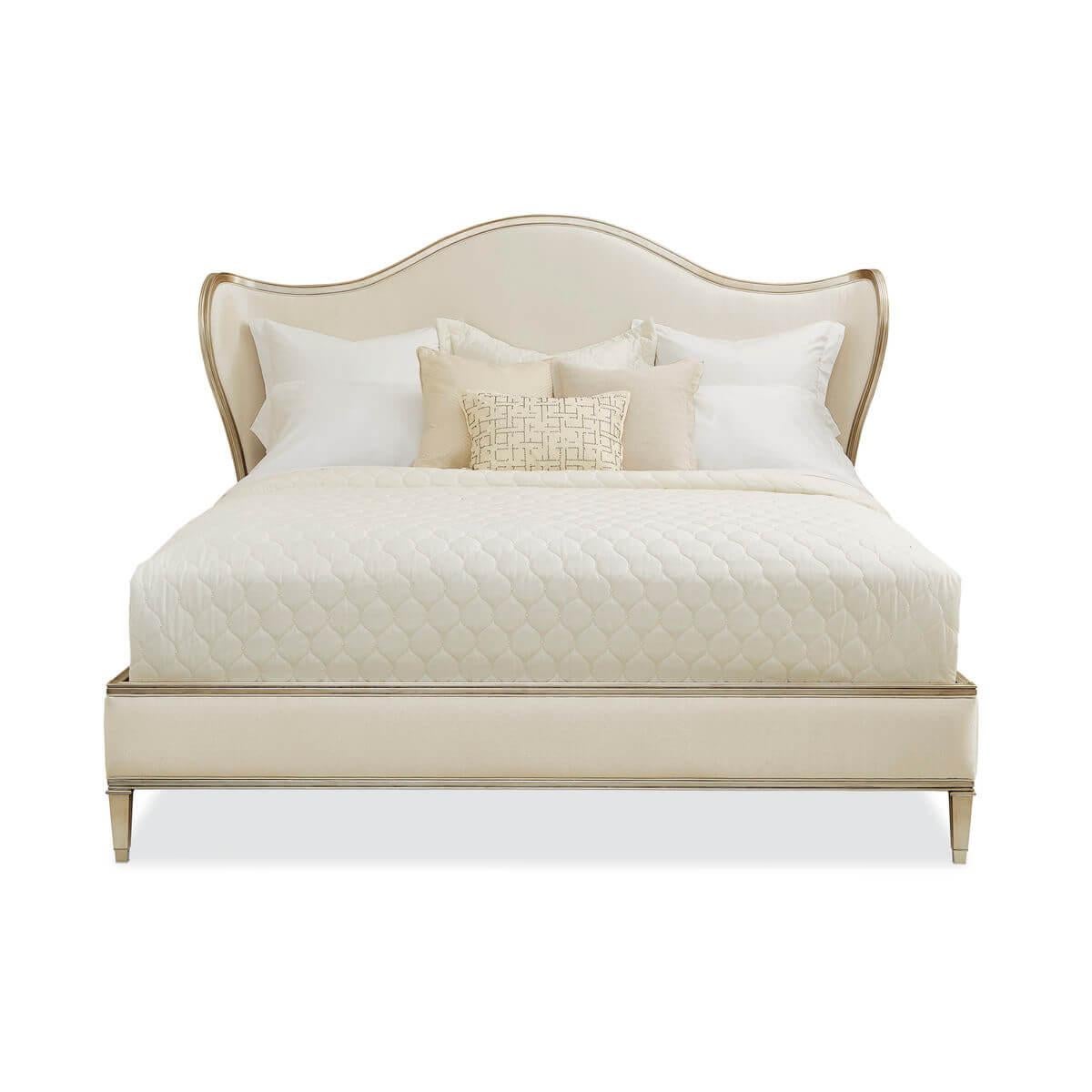 Queen Bed with a serpentine headboard and curved wings. The exposed carved wood rail is finished in radiant Auric silver leaf. Fully upholstered in a cream fabric. This piece has a low footboard and square-tapered carved feet.

Dimensions: 76