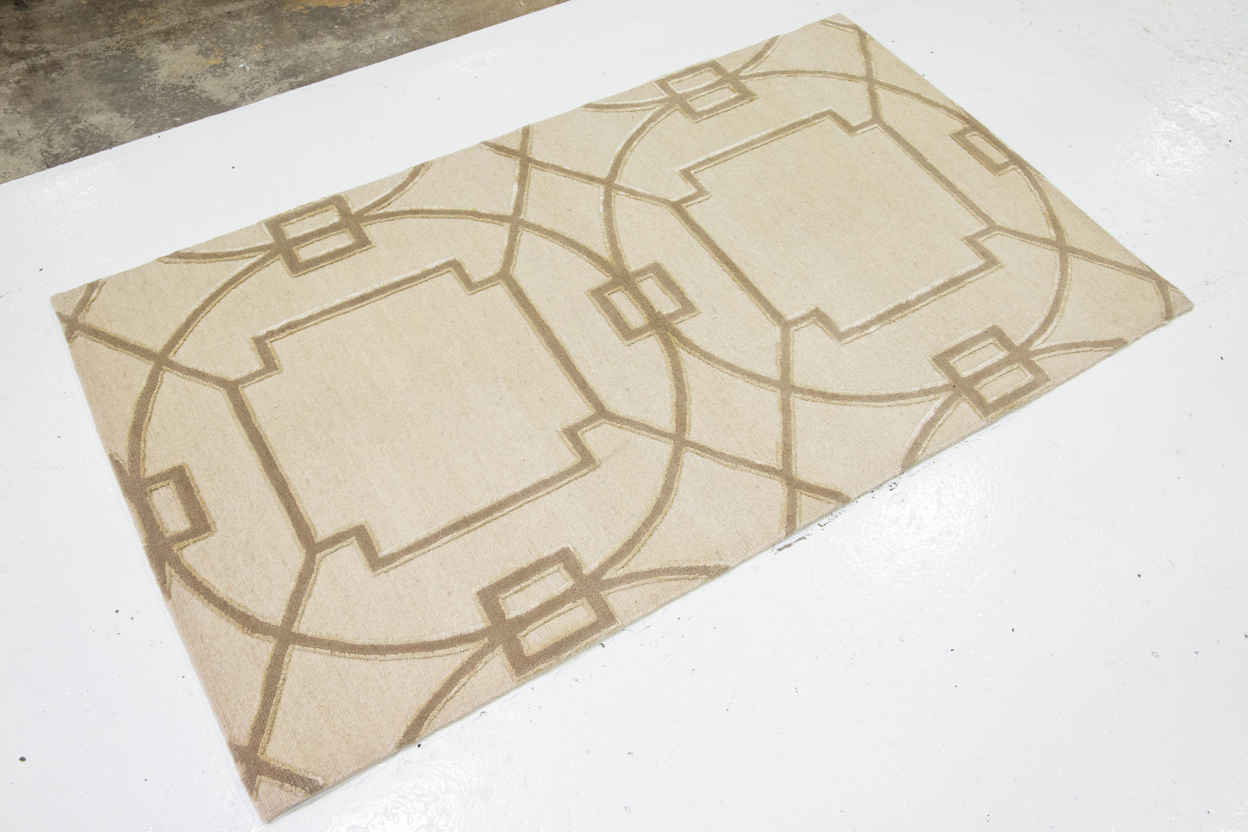 Questo tappeto personalizzato ha un campo beige di ispirazione orientale e un disegno geometrico marrone chiaro. È realizzato in lana tibetana e seta per un look elegante e invitante.

Il prezzo si basa su una superficie di 8' x 10'.