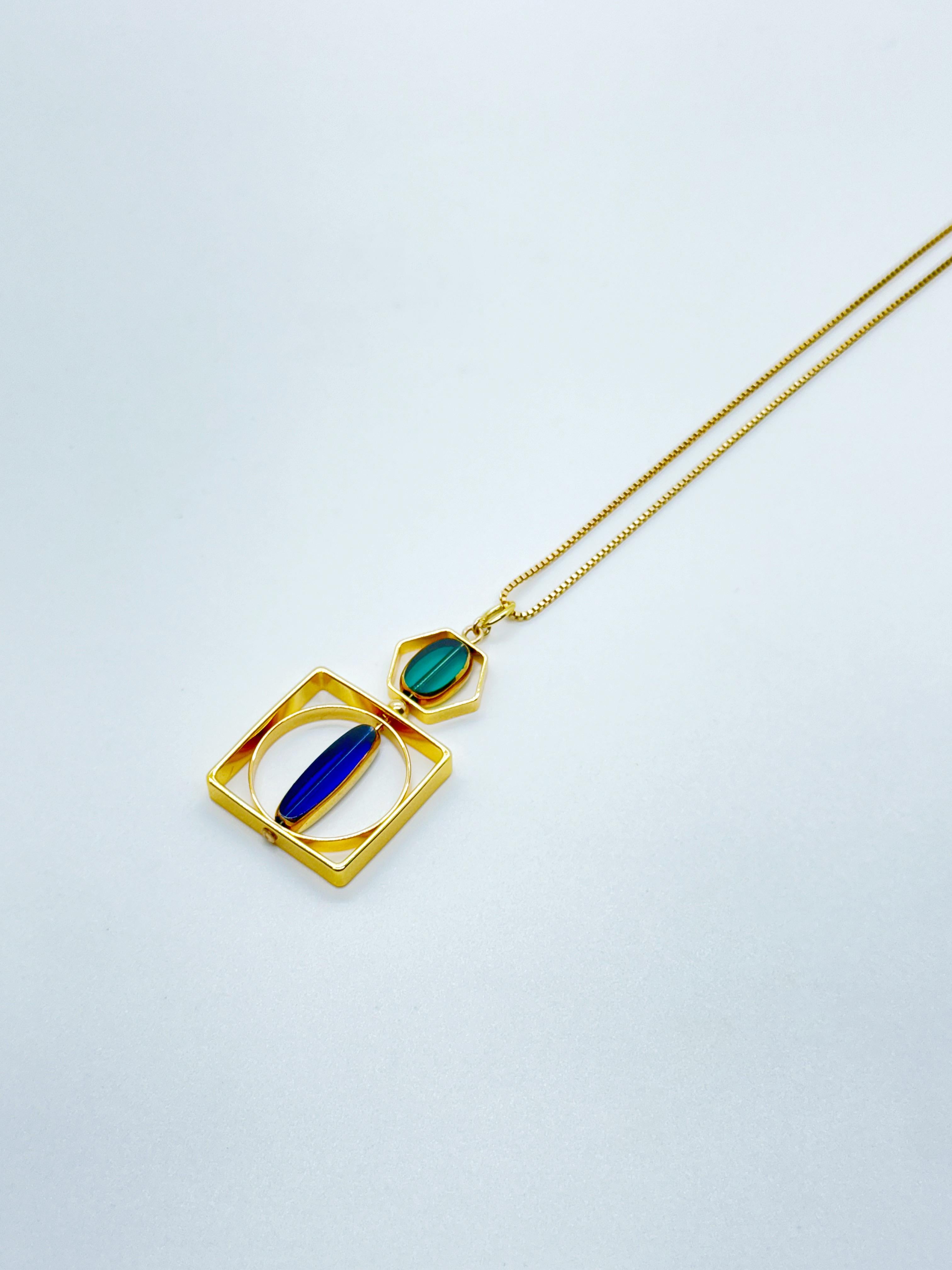 Le pendentif est composé de perles de verre allemandes vintage translucides bleues et vertes et se termine par une chaîne de 20 pouces en or. 

Les perles sont de nouvelles perles de verre allemandes vintage qui sont encadrées avec de l'or 24K. Les