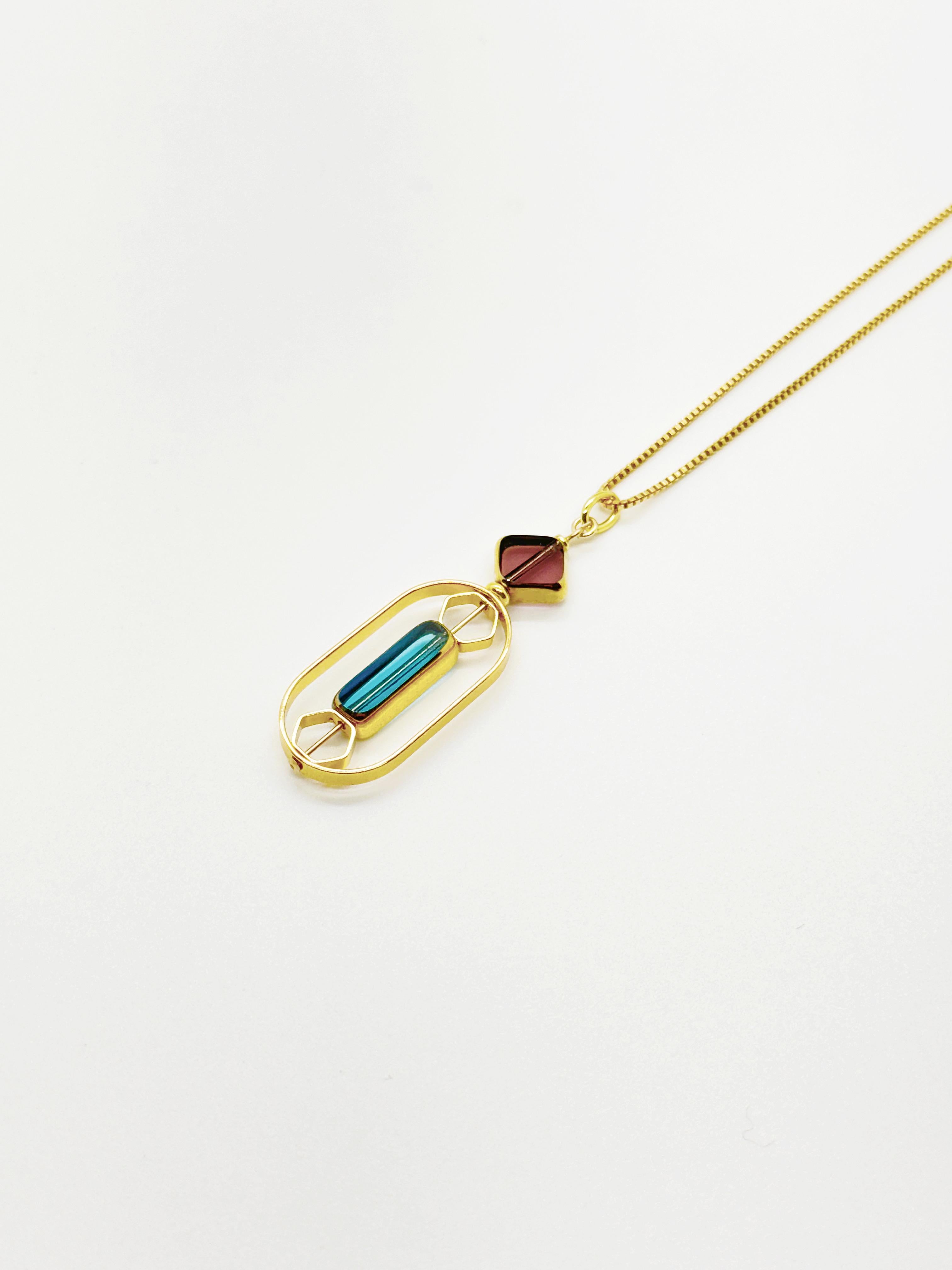 Le pendentif est composé de perles de verre allemandes vintage translucides bordeaux et bleu clair et se termine par une chaîne en or de 18 pouces. 

Les perles sont de nouvelles perles de verre allemandes vintage qui sont encadrées avec de l'or