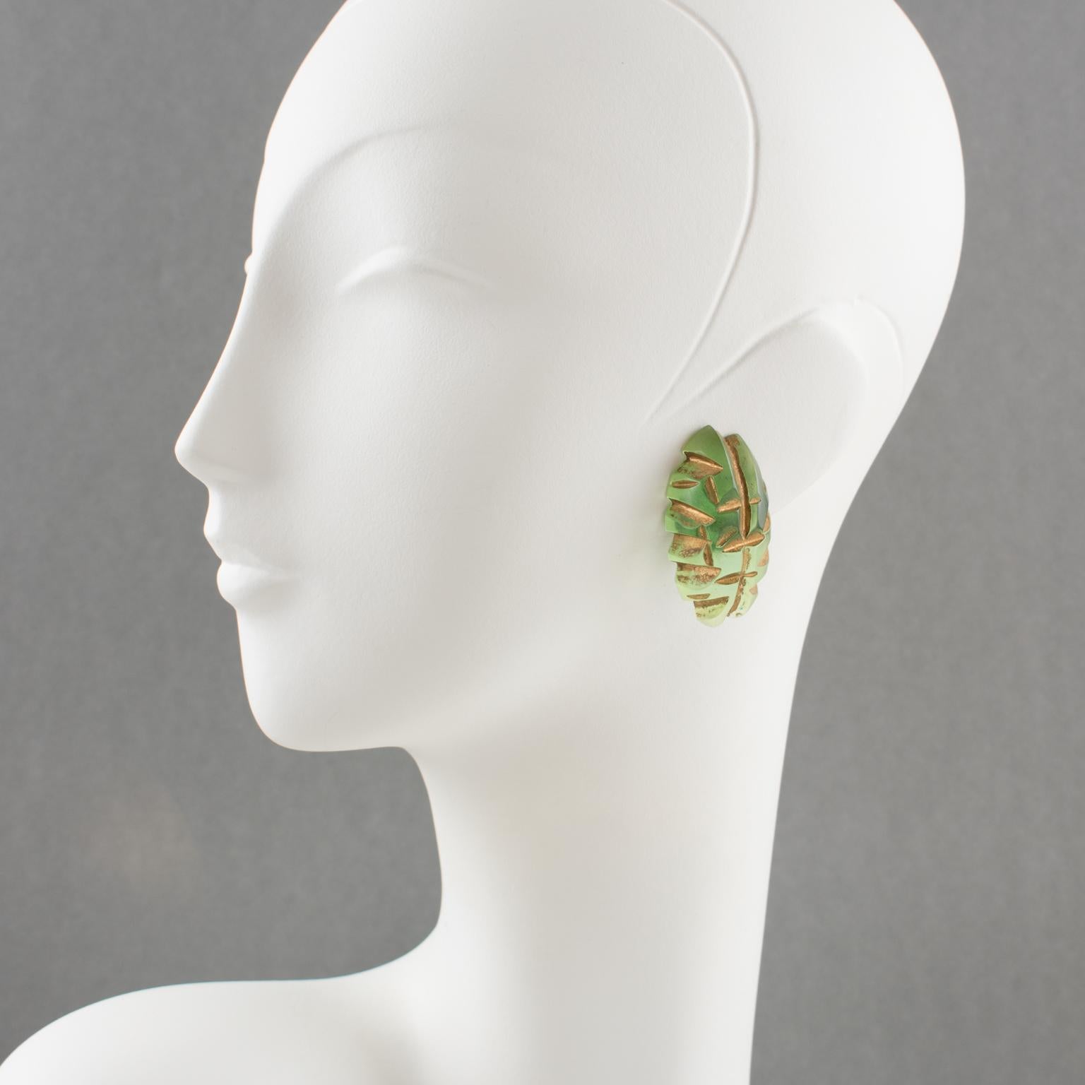 These elegant carved Lucite or resin clip-on earrings were crafted in the 1980s. The hand-made dimensional oval domed shape has a striped design in translucent fern green color and gold paint application in the carving. There is no visible maker's