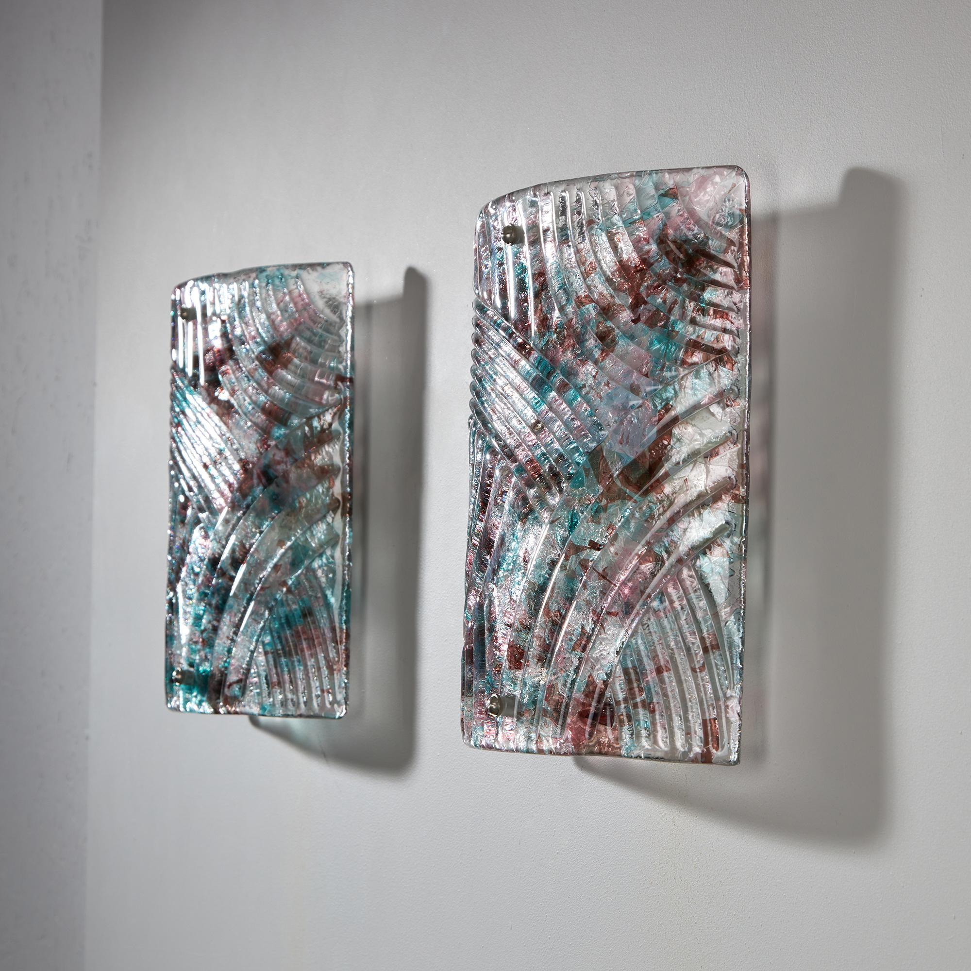 These wall lamps are not only functional but also captivating works of art, with their vibrant yet calming aesthetic. Made from translucent Murano glass, their square shapes are elegantly curved and their texture is mesmerizing. The blend of teal
