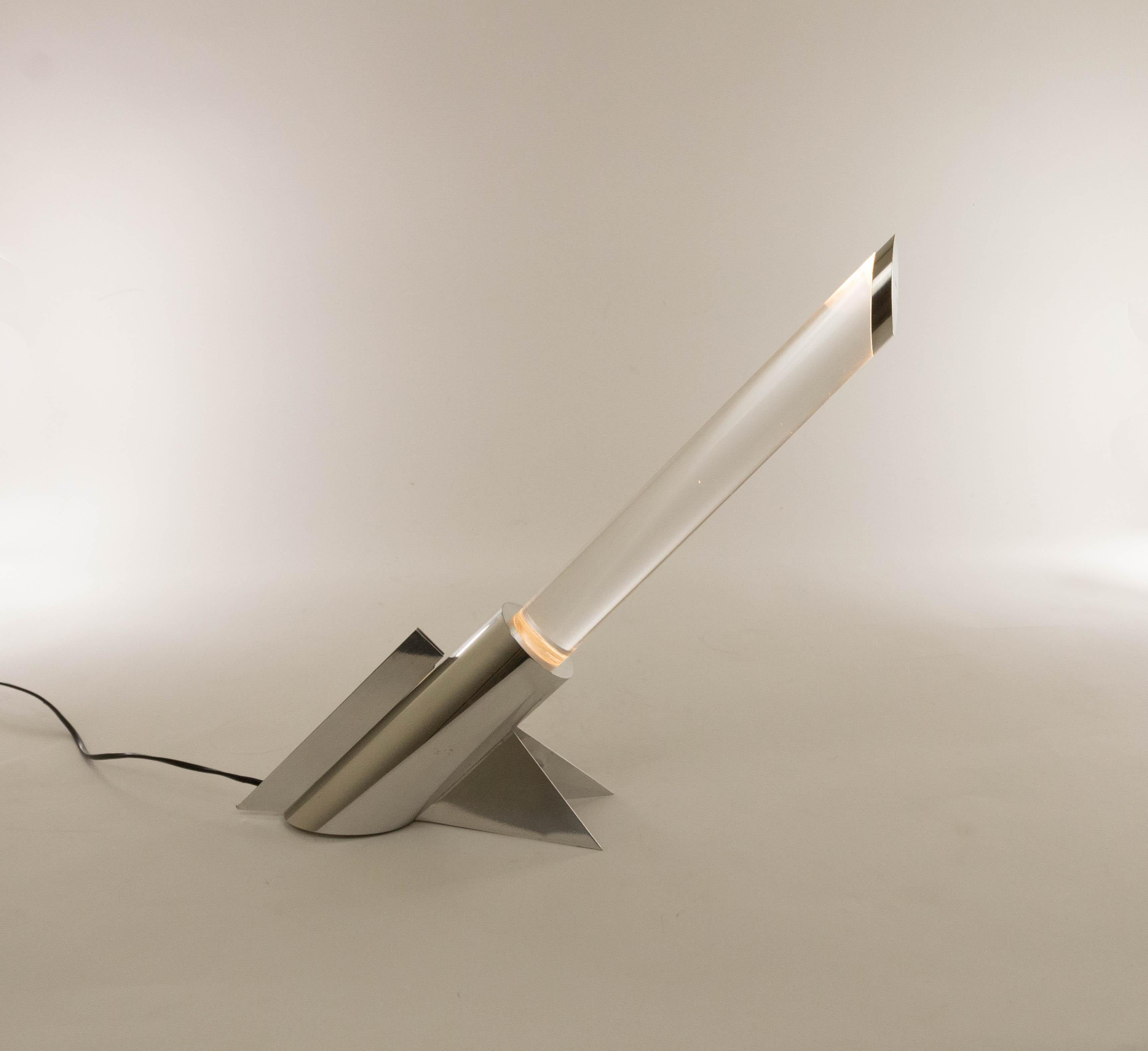Futuristic perspex table lamp by an unknown manufacturer from -most likely- Italy, probably produced in the 1970s.

The lamp consists of a metal chromed base containing the light source and a relatively heavy, massive transparent tube. The tube
