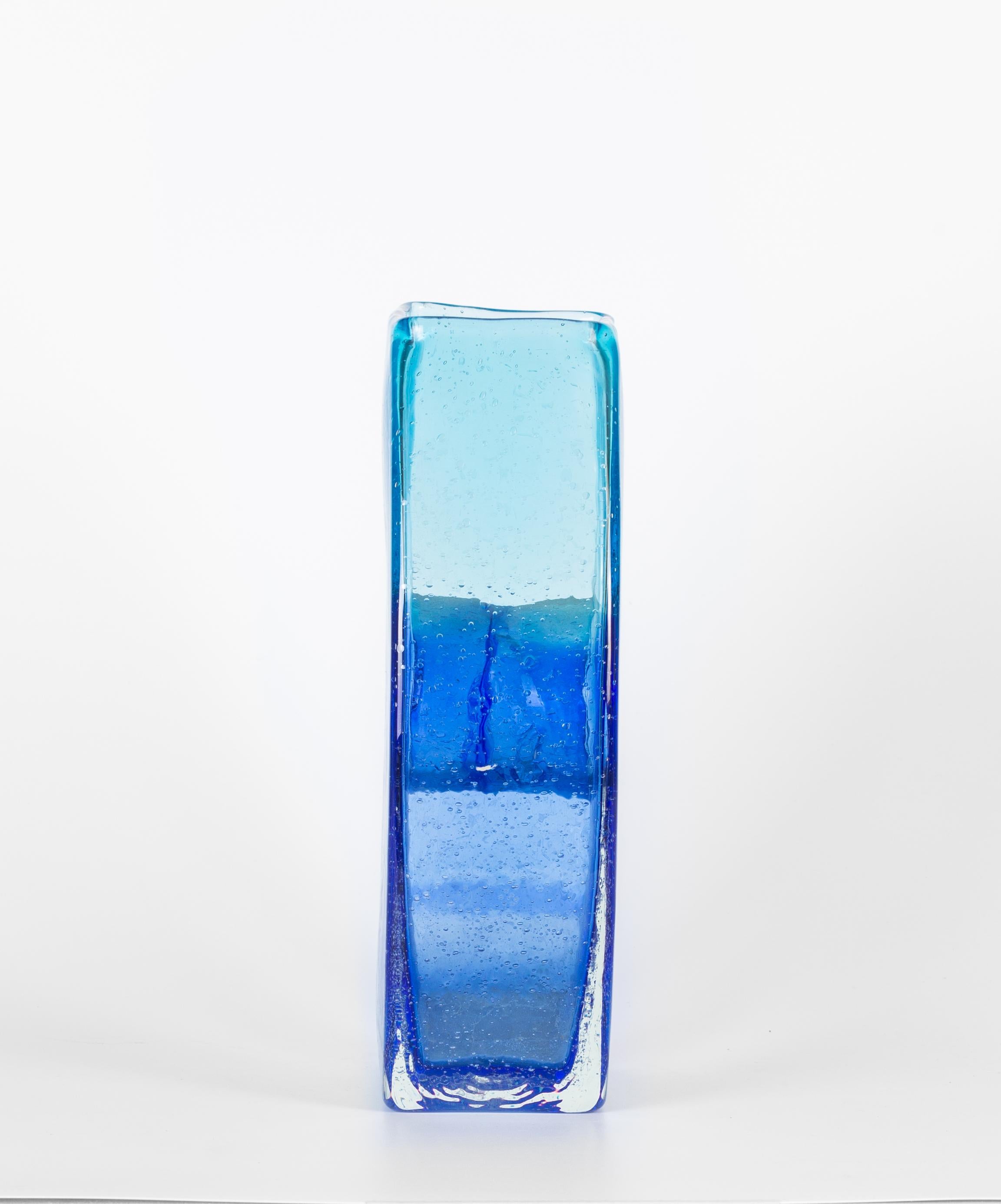 Transparent blue glass flowers vase is a beautiful glass decorative object, realized by a Murano manufacture during the 1970s. 

Very fashionable transparent blue colored vase with a circular shape in the center. 

This is the perfect vase to