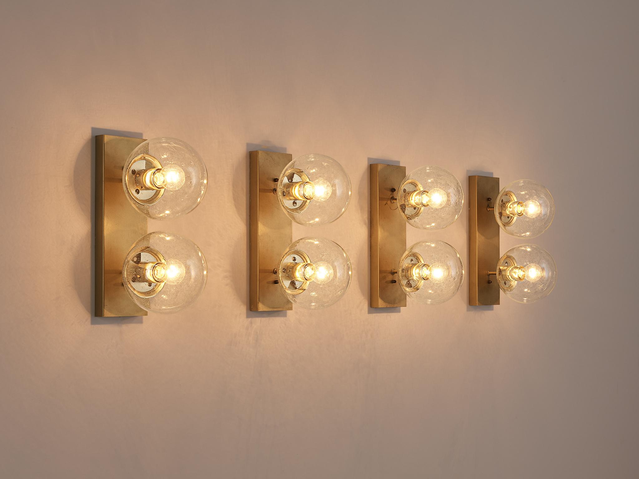 Wall lights, brass, opaline glass, Europe, 1960s. 

Set of four double wall sconces with clear glass shade. The bulbs are connected directly to a brass horizontal slat that goes directly on to the wall. Due to their sleek look and the combination