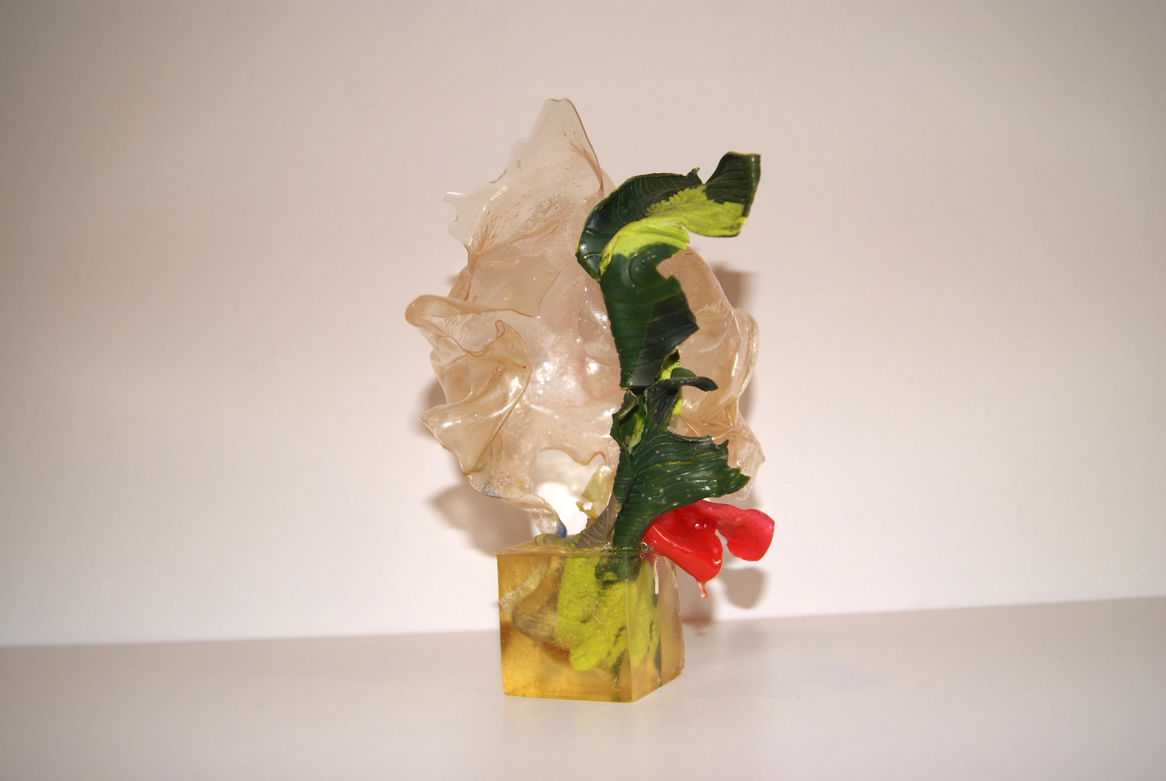 Green, red and clear biomaterial sculpture submerged in resin cube.