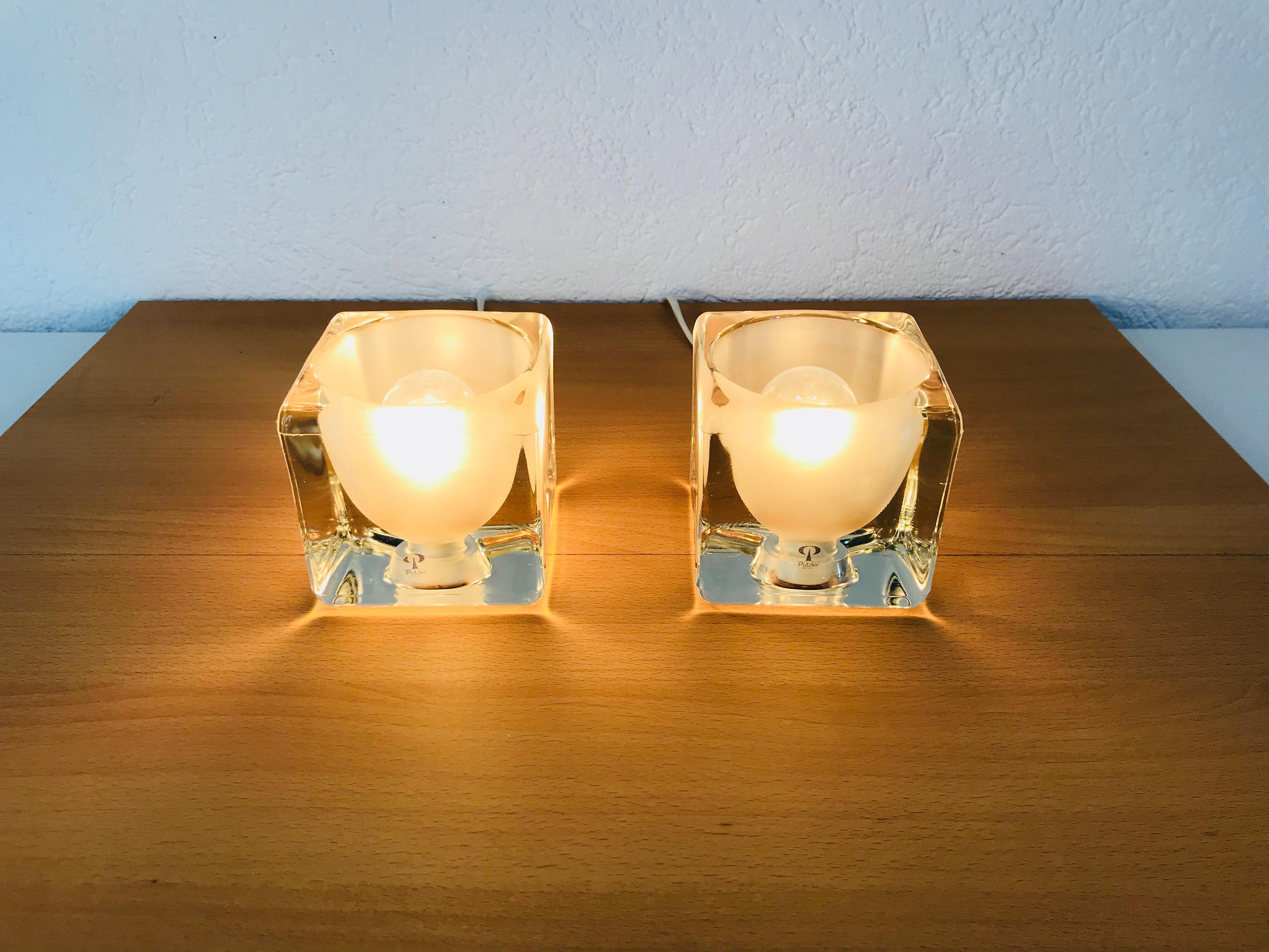 A beautiful pair of table lamps by Peill & Putzler made in Germany in the 1970s. They have a cube shape and are made of transparent ice glass. The original brand label is on both of the lights. They are in very good vintage condition.

The light