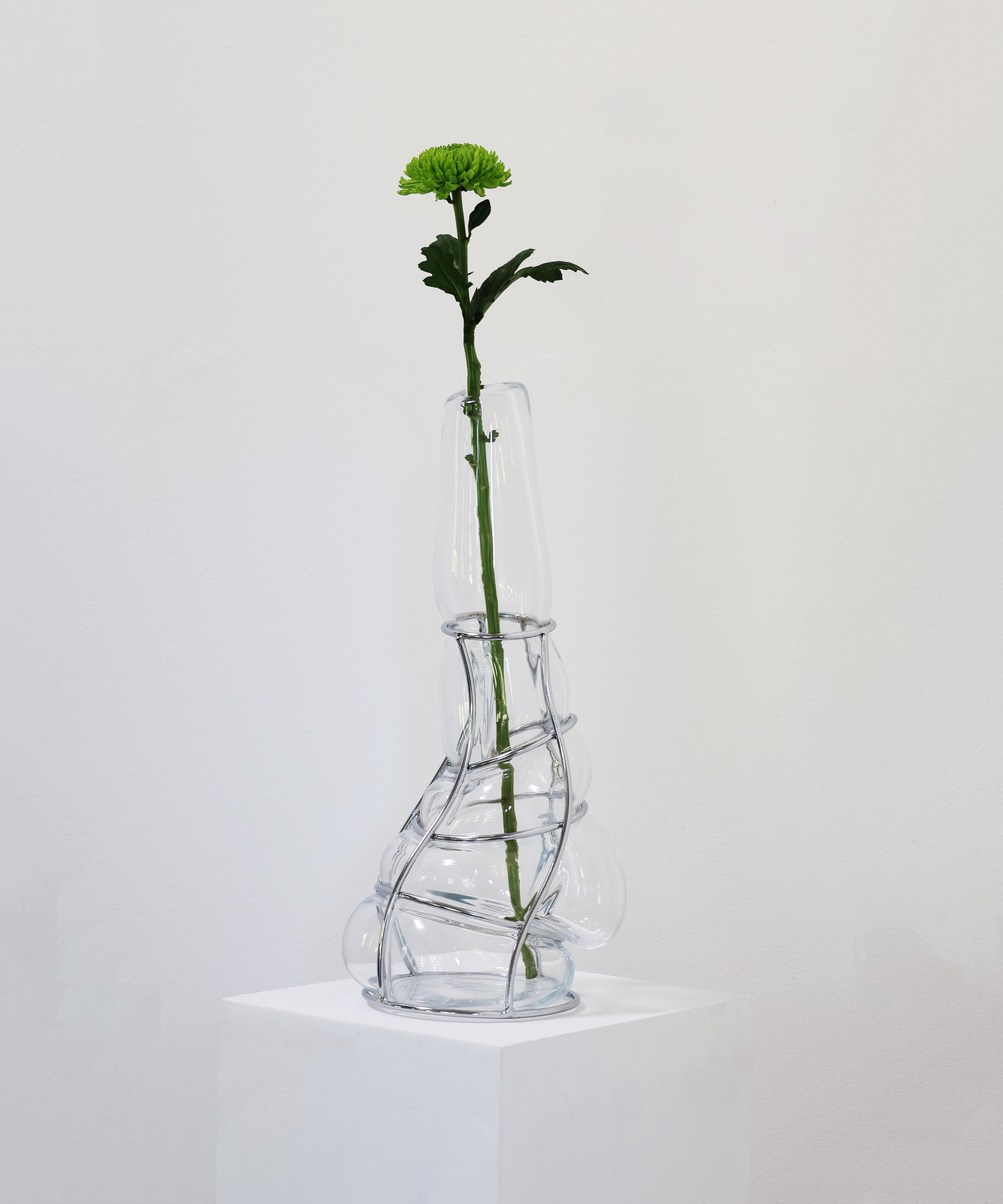 Vase sculptural Babà à long col transparent d'Alice Crepaldi
Pièce unique.
Dimensions : Ø 23 x H 51 cm : Ø 23 x H 51 cm.
Matériaux : Verre de Murano et métal.

Orné d'une tige légèrement plus courte mais élégante, ce vase ingabbiato utilise la