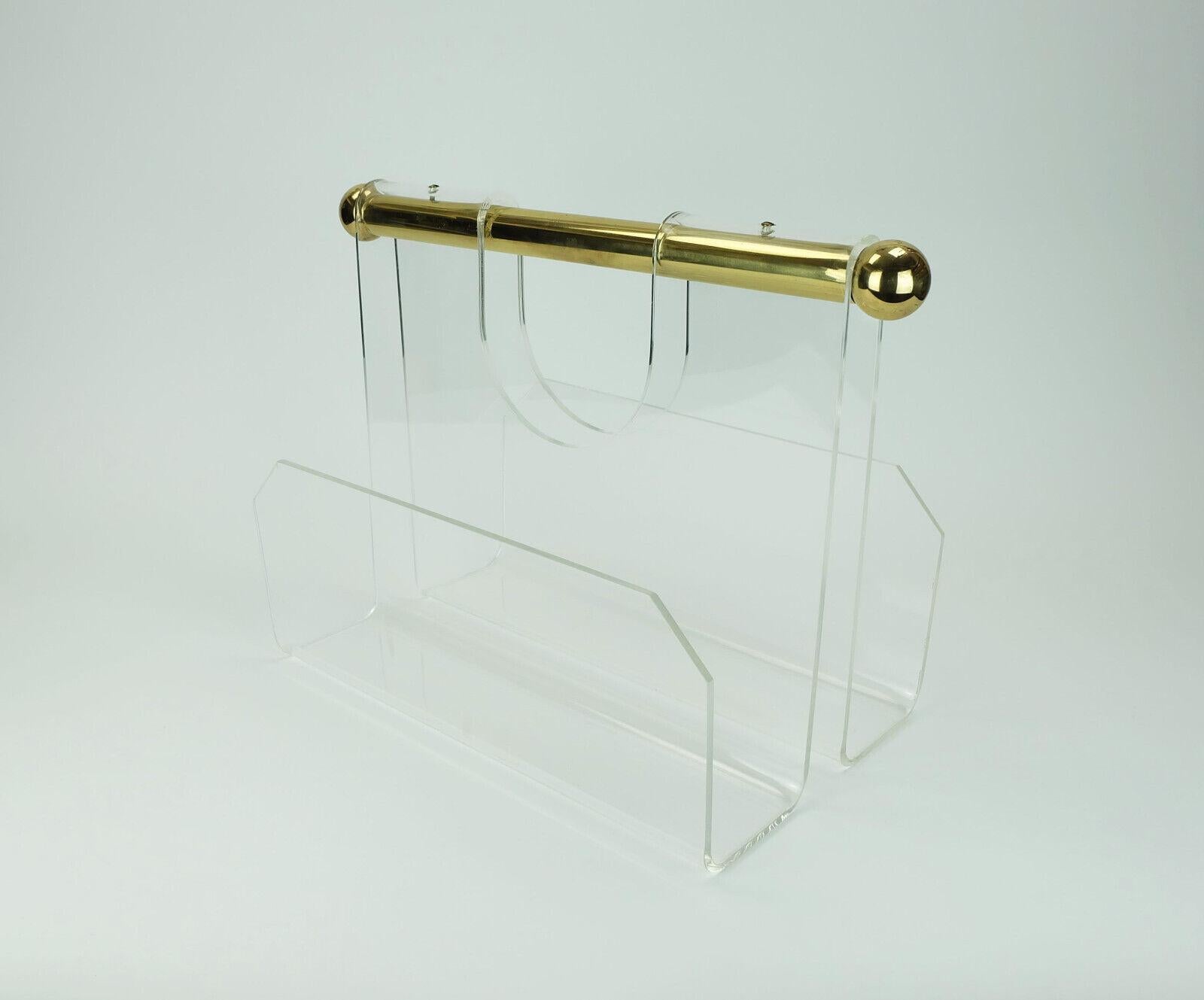 Magazine rack with 2 compartments, made of acrylic with a thick round brass handle.

Dimensions in cm:
Width 40 cm (incl. handle 47 cm), depth 27 cm), height 34 cm, width per compartment 10.5 cm.

Dimensions in inches:
Width 15.74