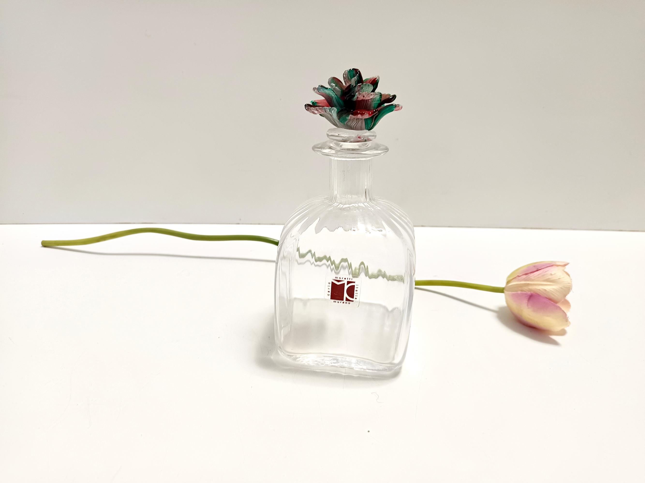Made in Italy, in 1980s. 
The decanter is made in ribbed hand-blown Murano glass with a modeled polychrome glass cap.
This is a vintage piece, therefore it might show slight traces of use, but overall it can be considered as in excellent original