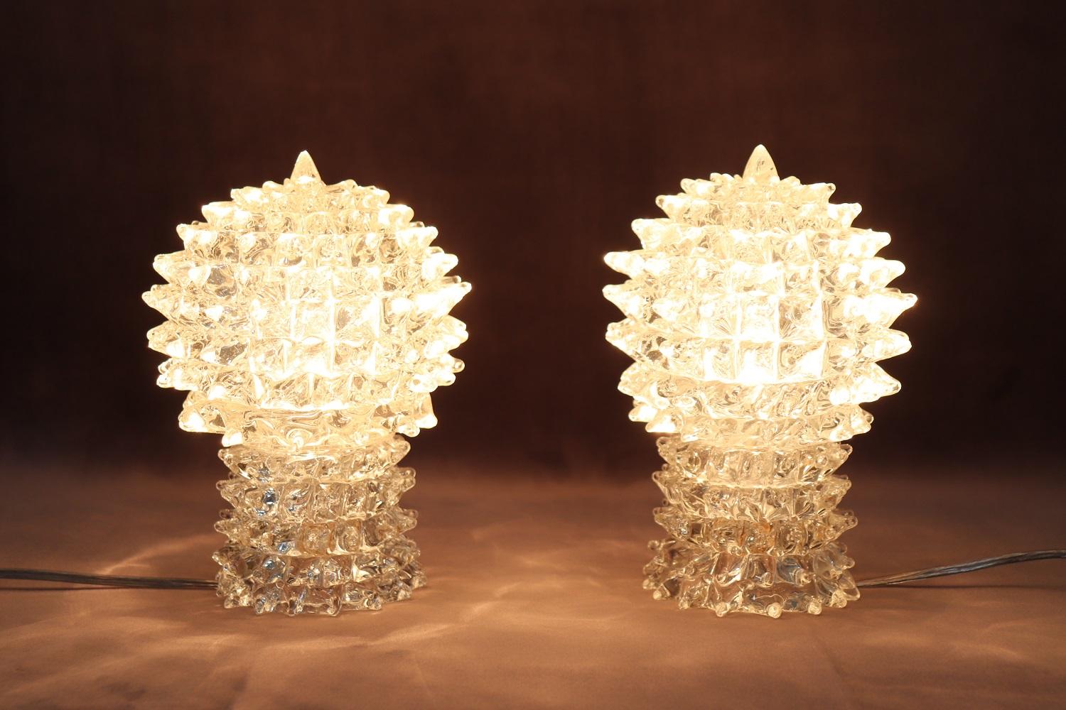 Fantastic pair of Italian design table lamps from around 1940s. Made of precious transparent Murano glass. Characterized by a particular shape with the glass has a particular pointed decoration called rostrato. Perfect for placing on bedside tables.