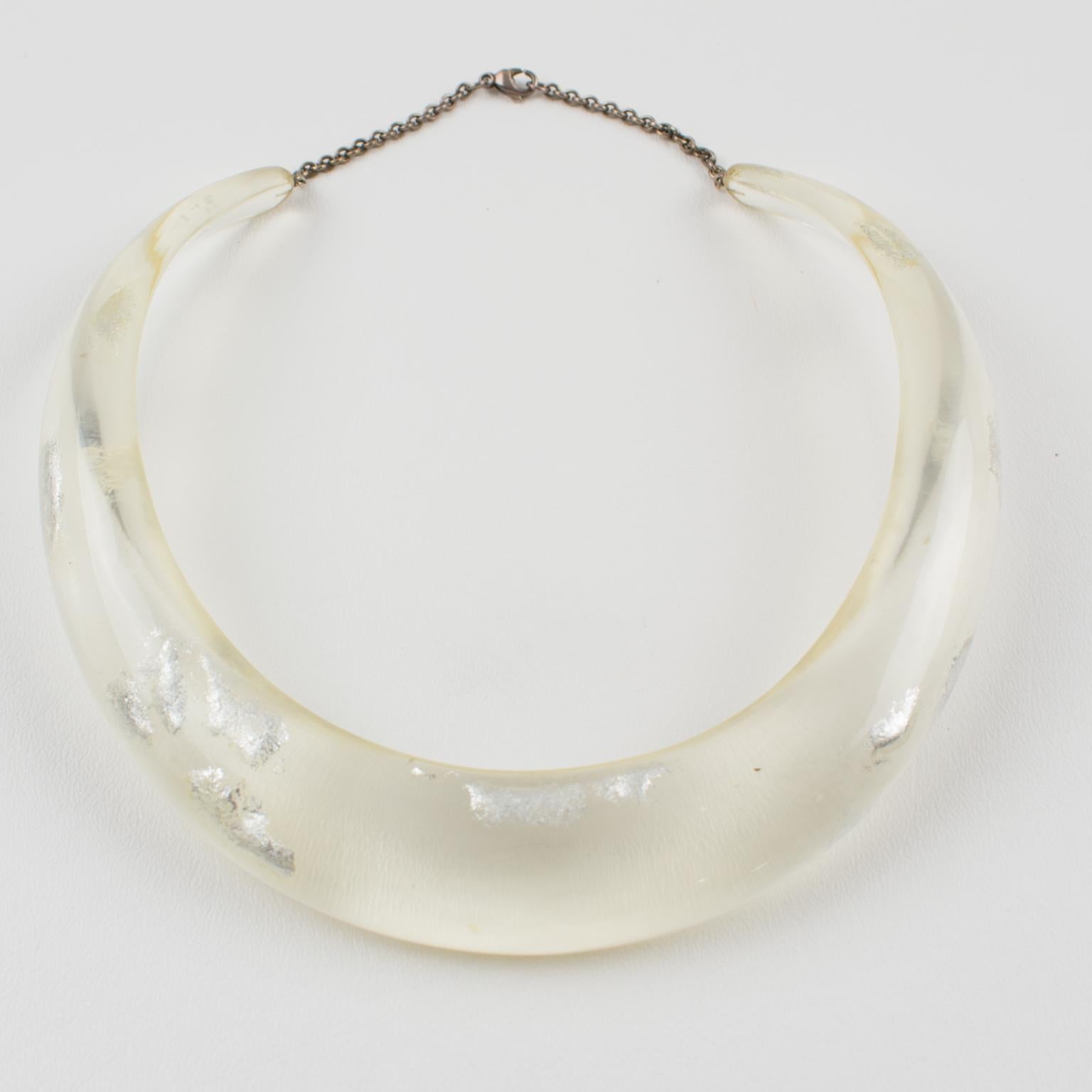 Questa elegante collana girocollo di un artigiano-designer italiano vanta una forma a pettorina rigida in lucite o resina di colore trasparente traslucido, completata da inclusioni di scaglie d'argento in un design organico, astratto e libero. Una
