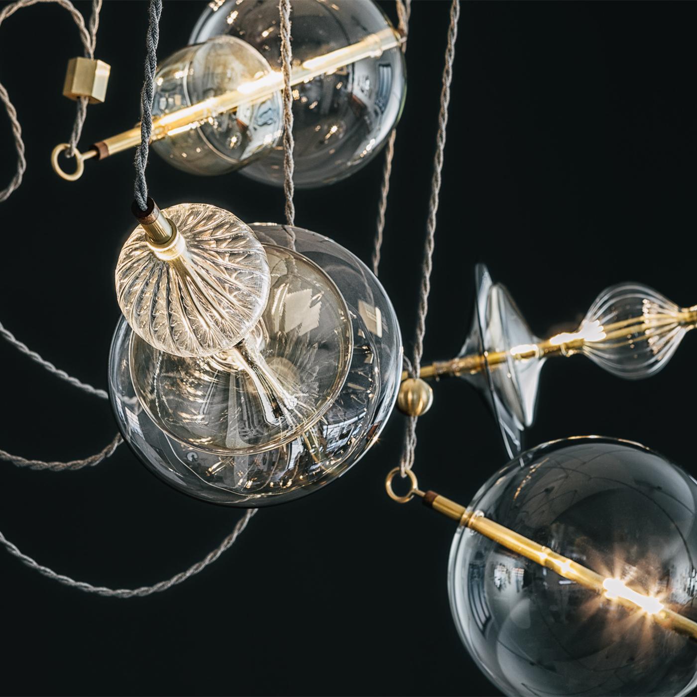 Inspired by a circus trapeze act, the Trapezi is a stunning contemporary chandelier finished and assembled in Italy. The unique lighting fixture combines hand blown glass, transparent or hand painted A Lustro which mixes color with gold particles,