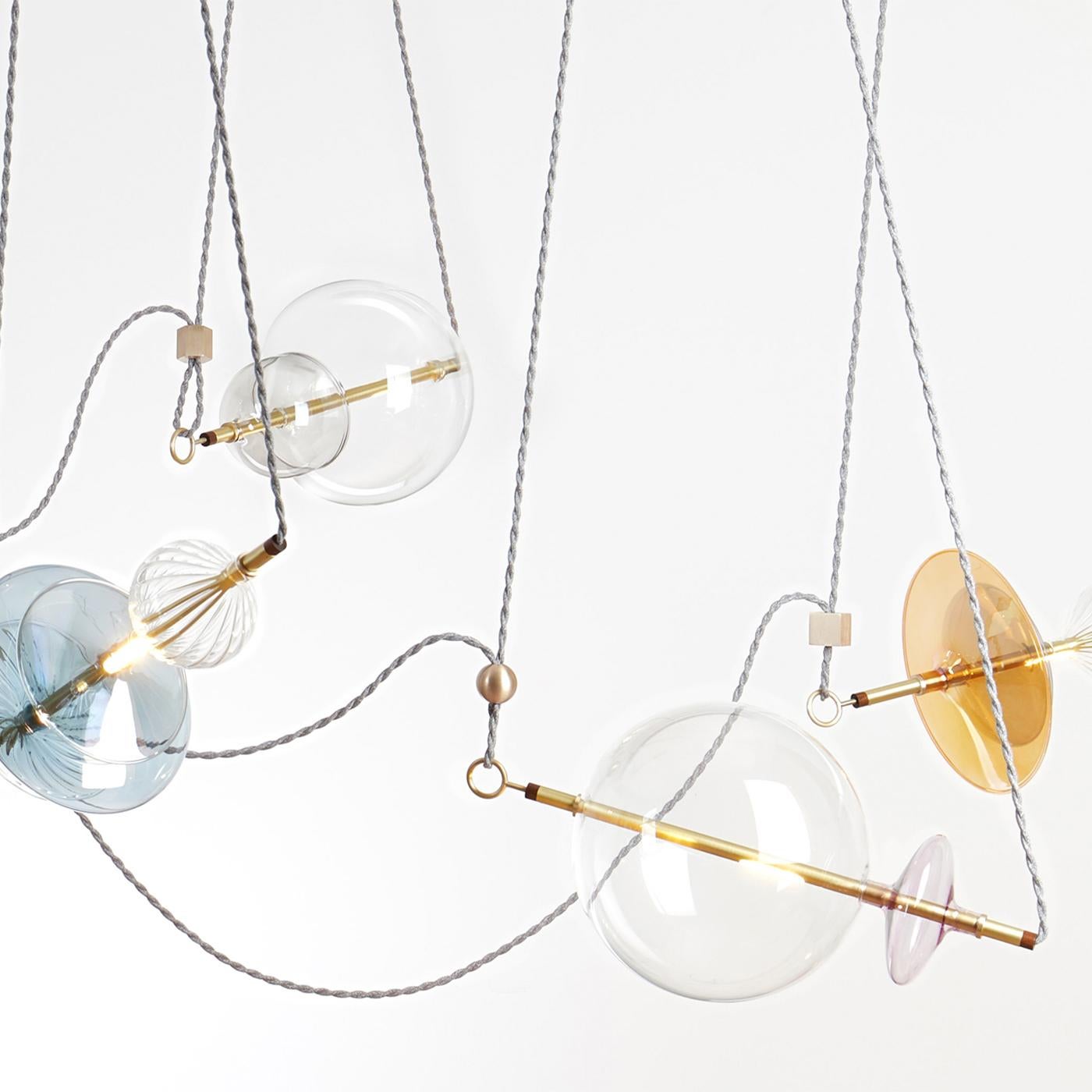 The Trapezi is a stunning contemporary chandelier inspired by a circus trapeze act and finished and assembled in Italy. The spectacular lighting fixture combines handblown glass, transparent or hand-painted A Lustro which mixes color with gold