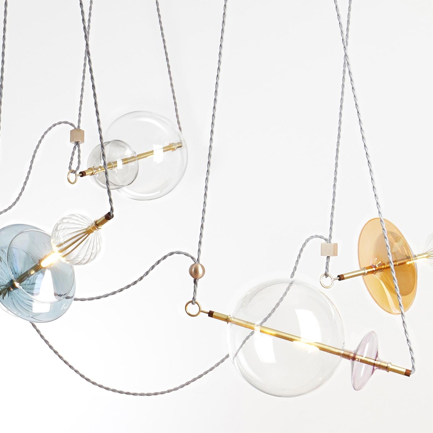 Il Trapezi è uno straordinario lampadario contemporaneo ispirato a un numero di trapezio del circo e rifinito e assemblato in Italia. Questo spettacolare apparecchio di illuminazione combina vetro soffiato a mano, trasparente o dipinto a mano A